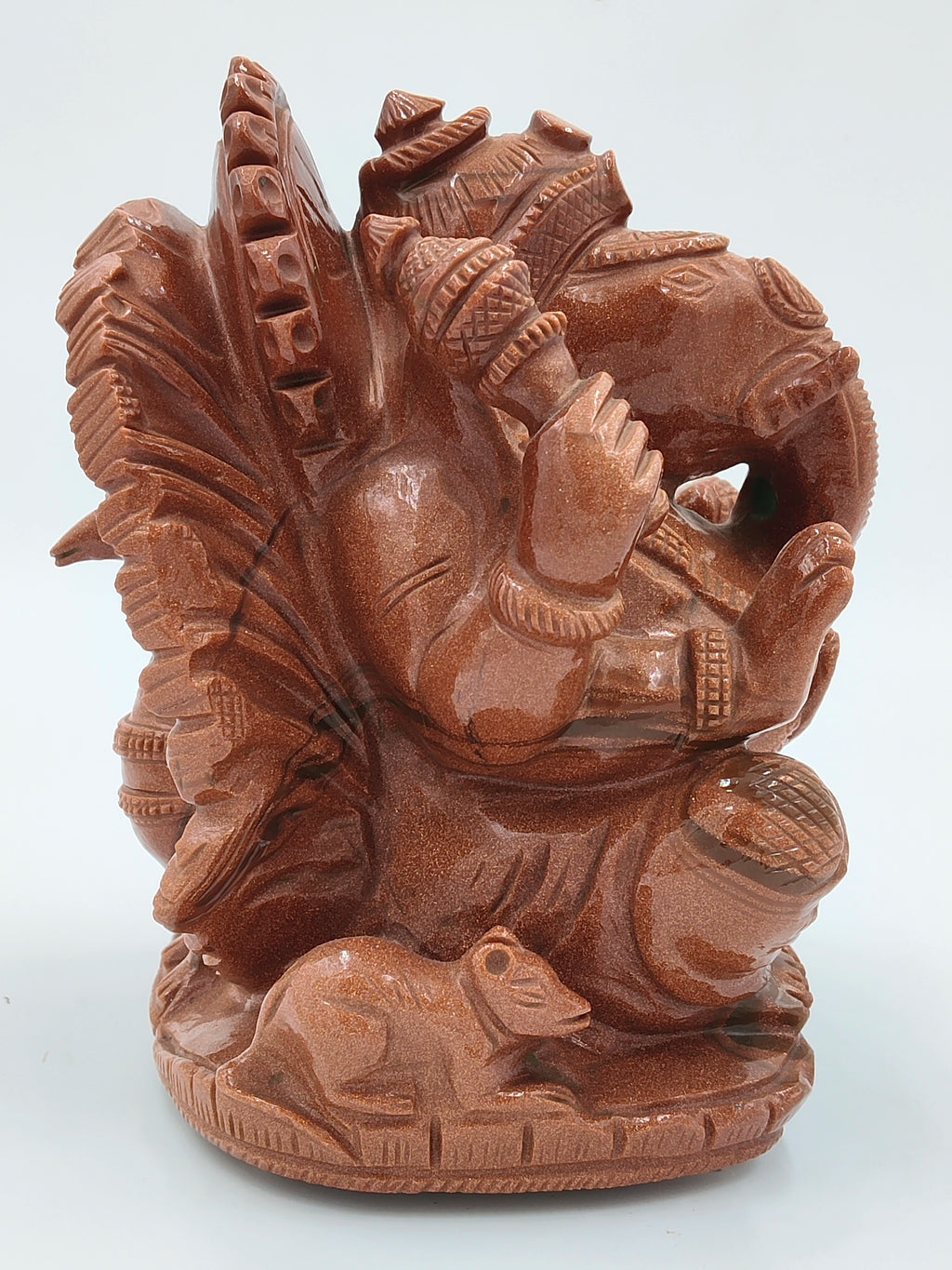 Carved sunstone statue of seated Ganesh with a mouse at the base