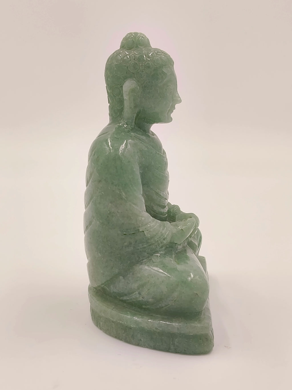 Side view of 4.3 inch jade Buddha sculpture sitting on a pedestal