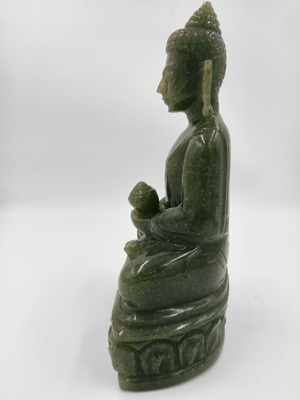 Side view of green jade Buddha statue seated on lotus pedestal