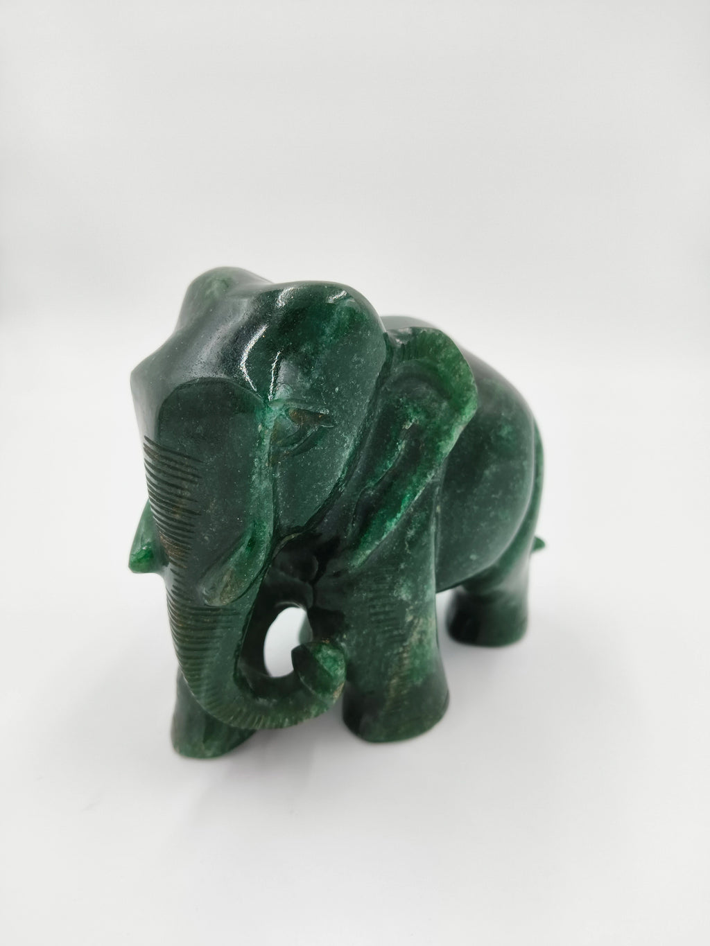 Small green jade elephant sculpture with carved details side view