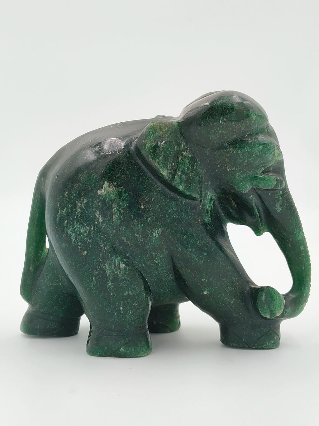 Green jade elephant sculpture with raised trunk holding a ball