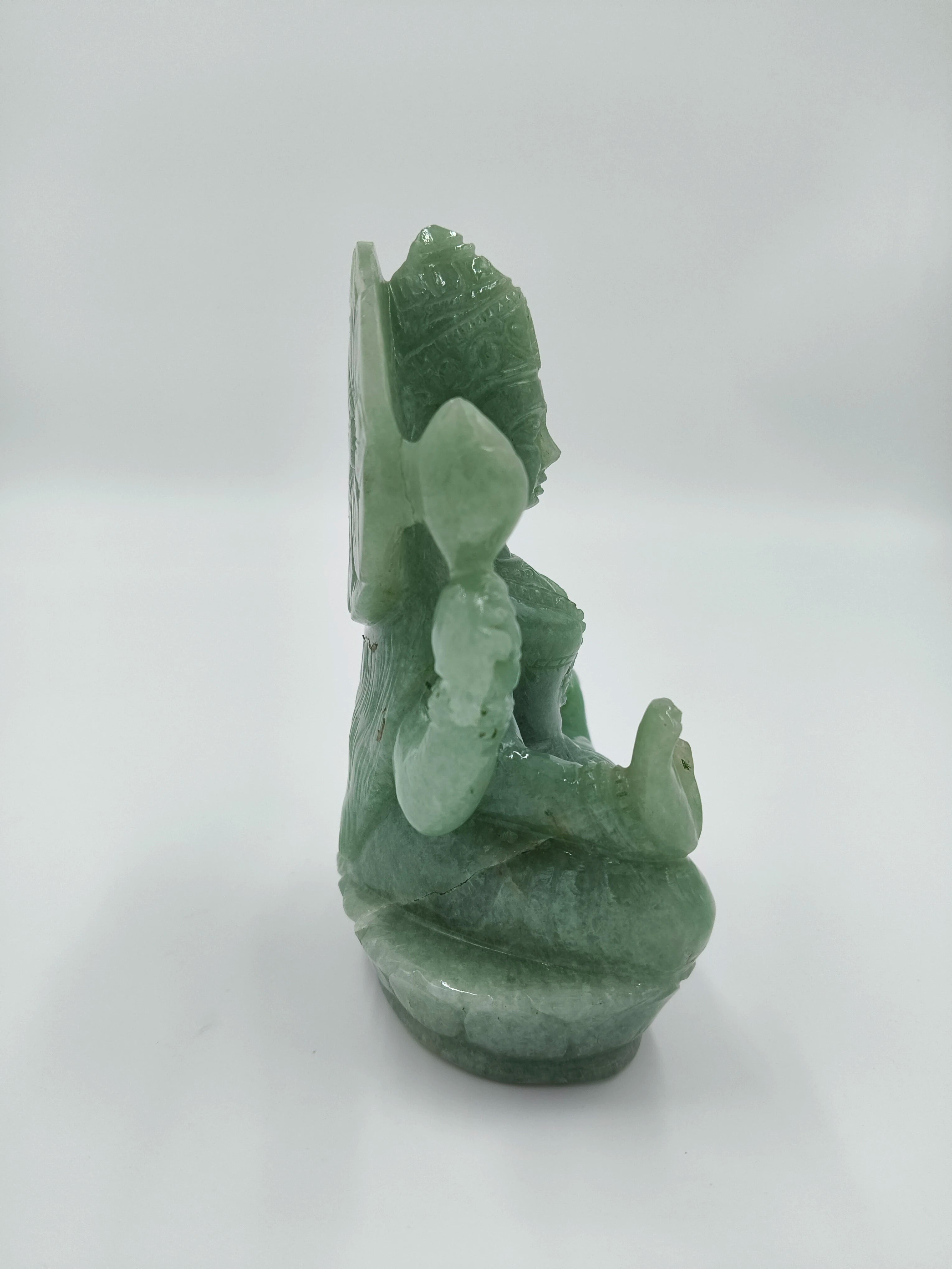 Side view of a jade Lakshmi statue with detailed carvings and a seated pose