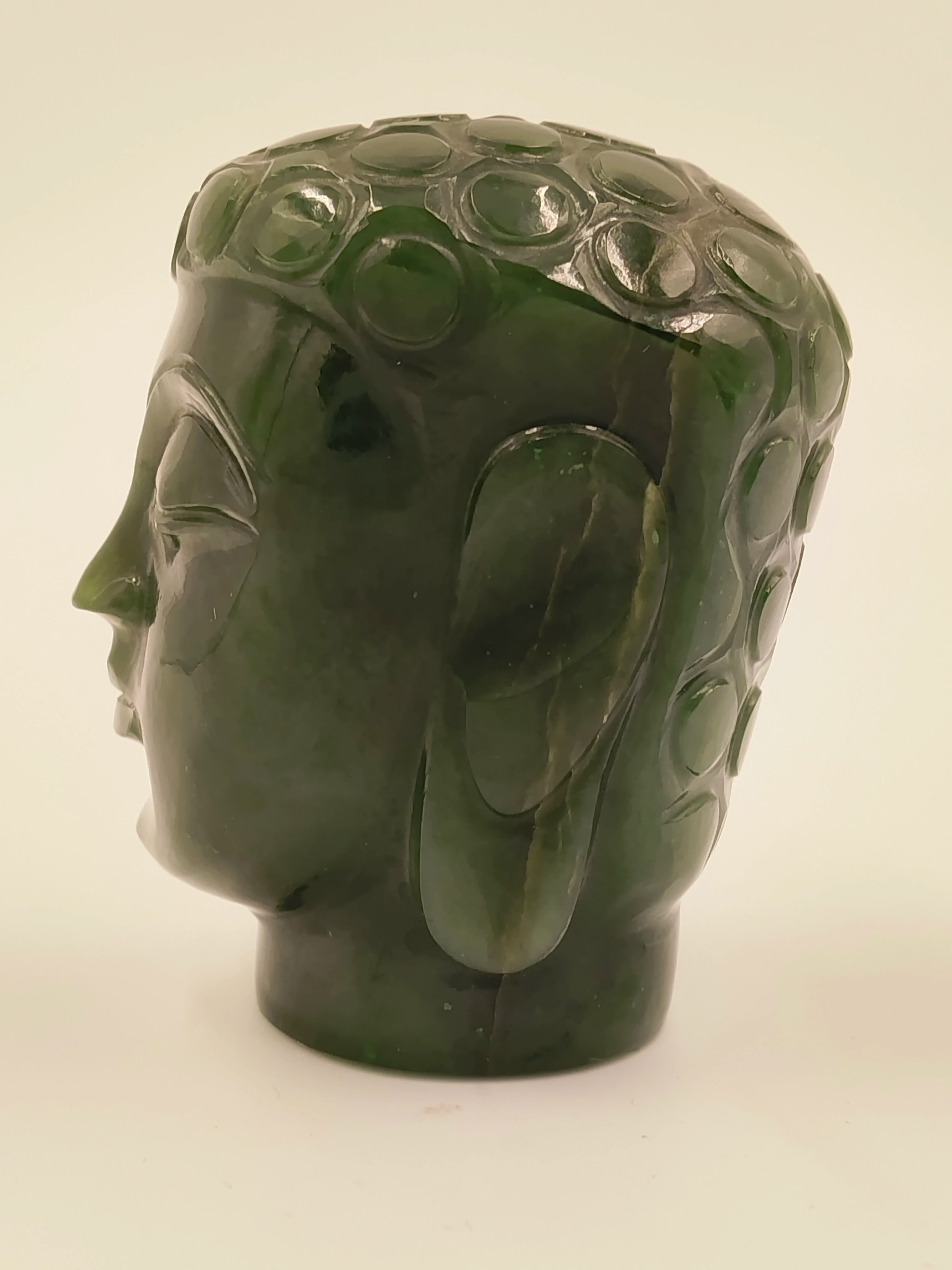 Side view of small jade Buddha head sculpture with detailed hair curls