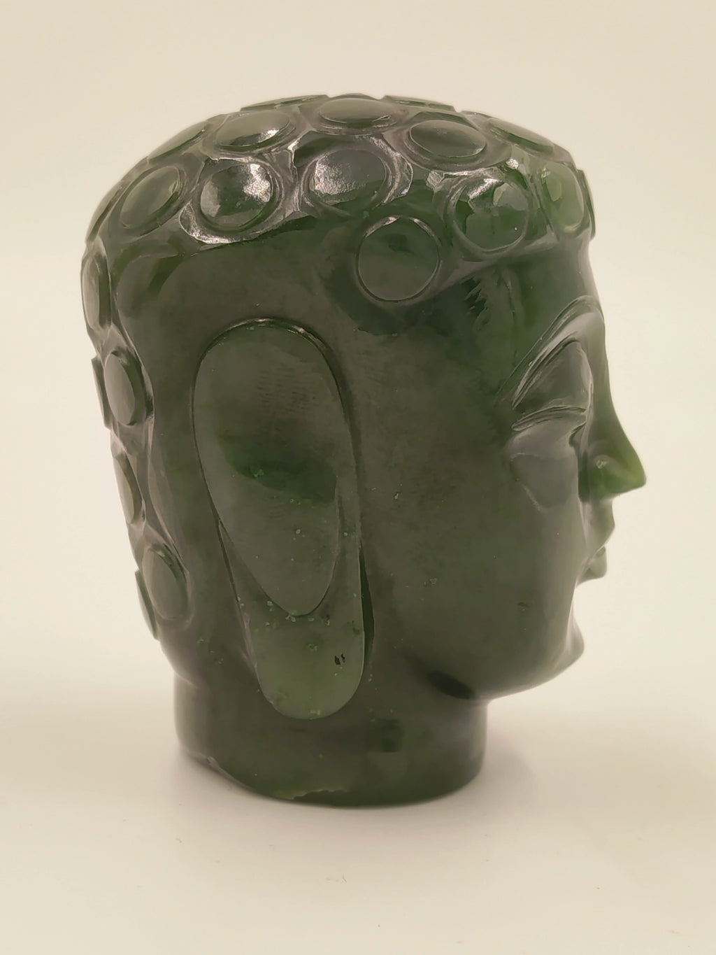 Side view of a small green jade Buddha head sculpture