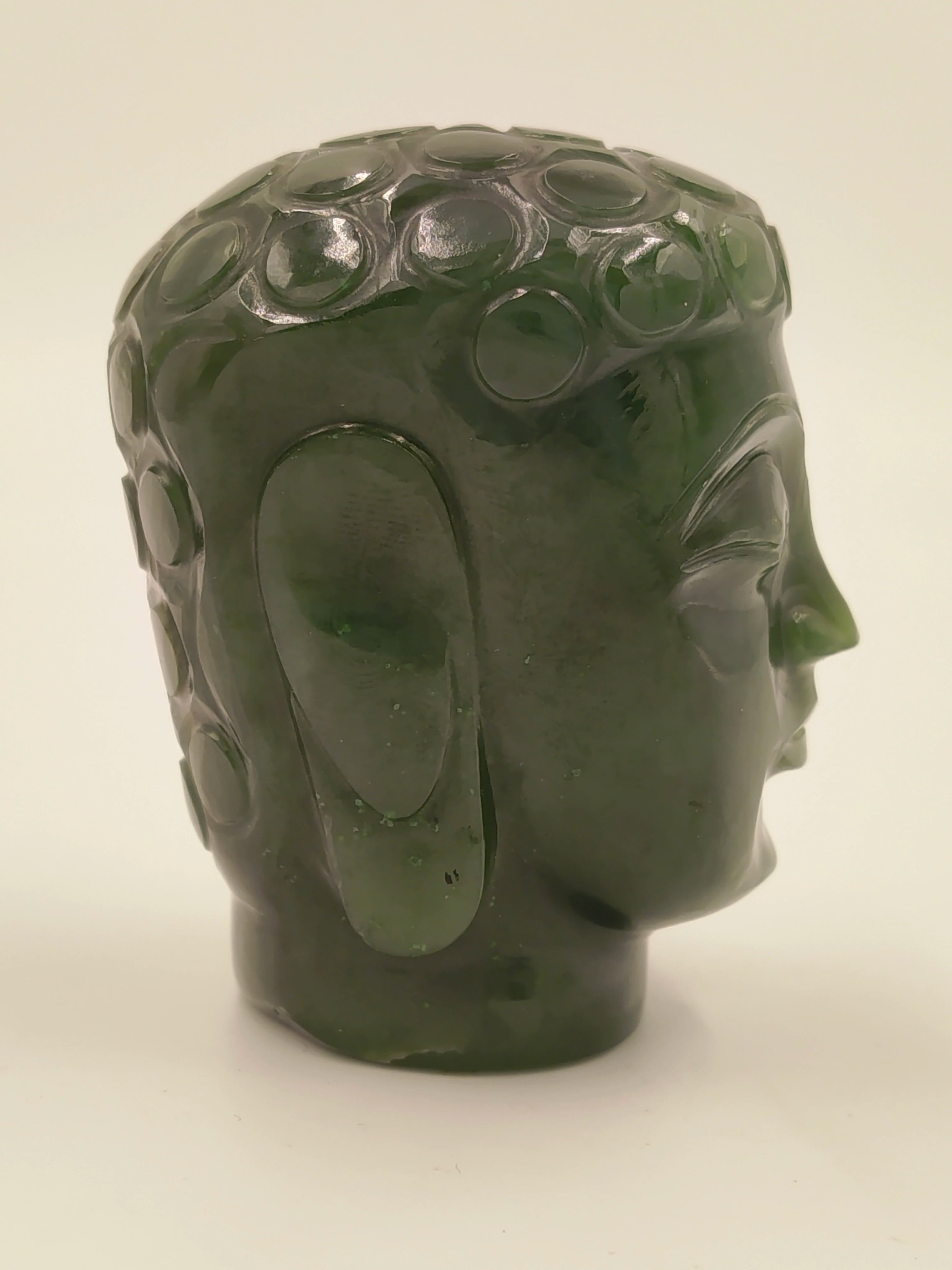 Side view of a small green jade Buddha head sculpture