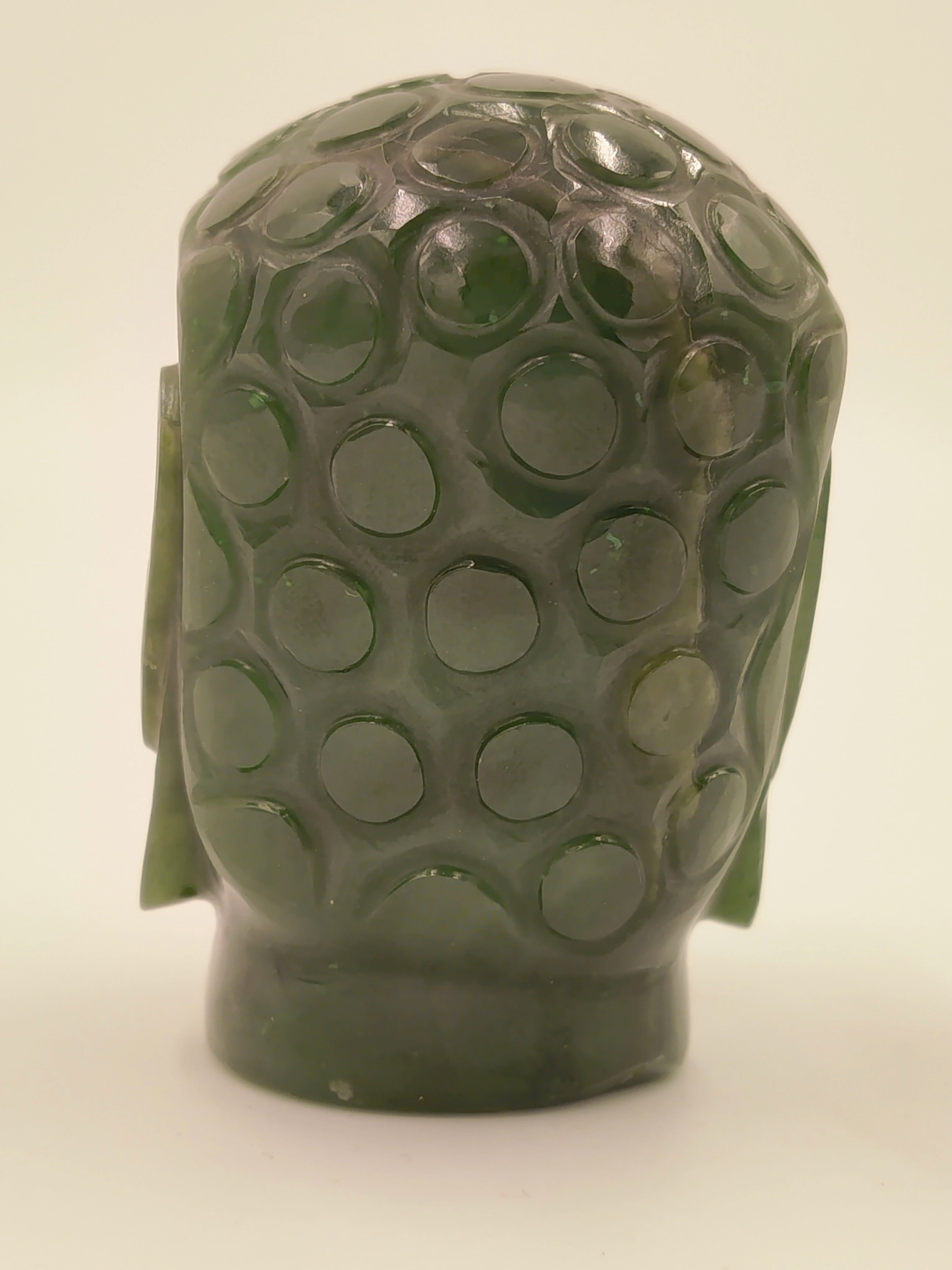 Back view of small jade Buddha head sculpture with circular patterns