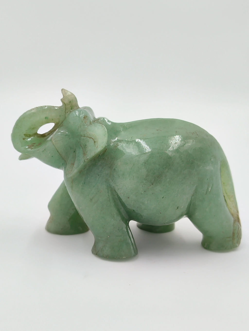 Small green jade elephant figurine with raised trunk, side view