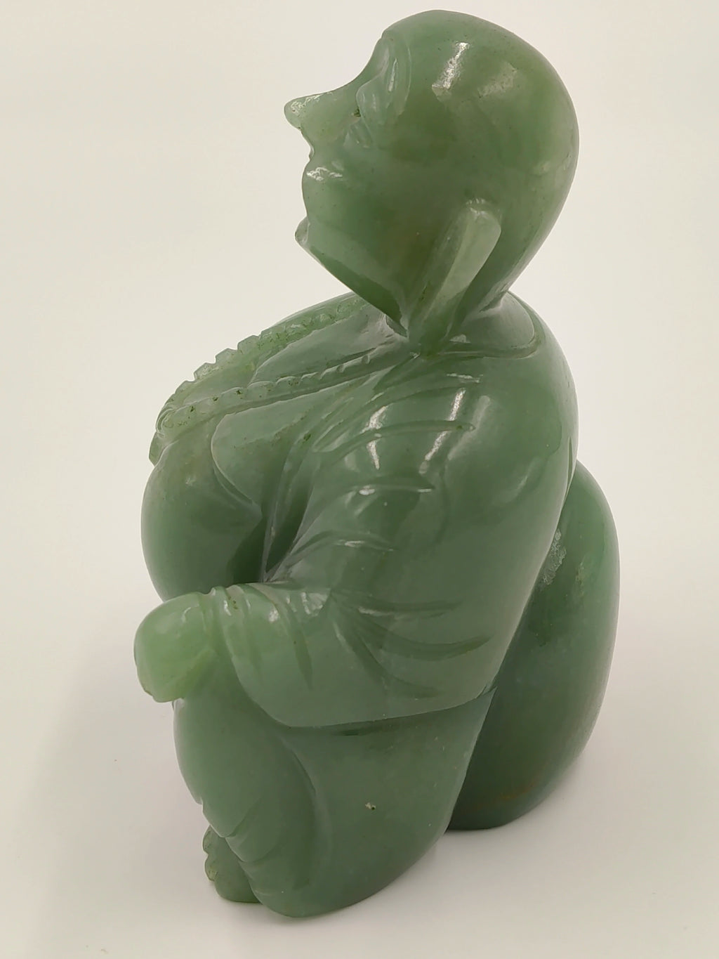 Side view of a small jade Laughing Buddha idol sculpture