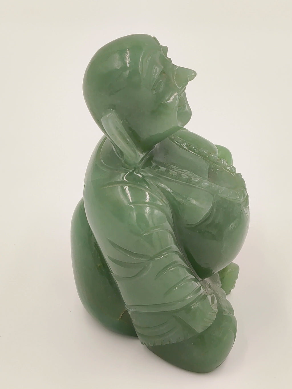 Side view of small jade Laughing Buddha idol with detailed carving
