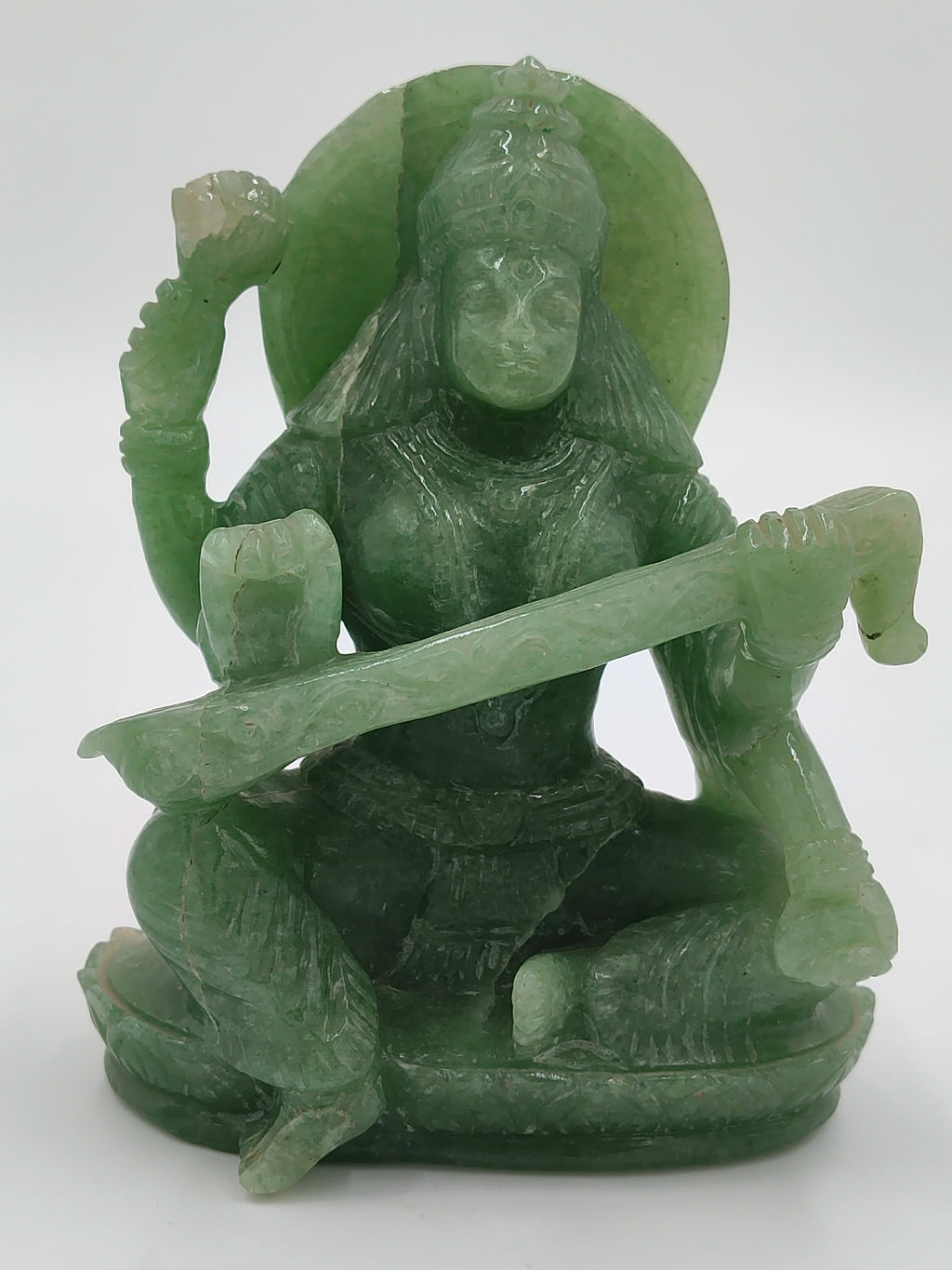 Green jade sculpture of deity Saraswathi seated playing veena with lotus flower
