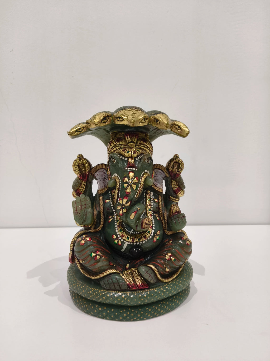 Large jade Ganesh statue with multi-painted details seated under a hood of snakes