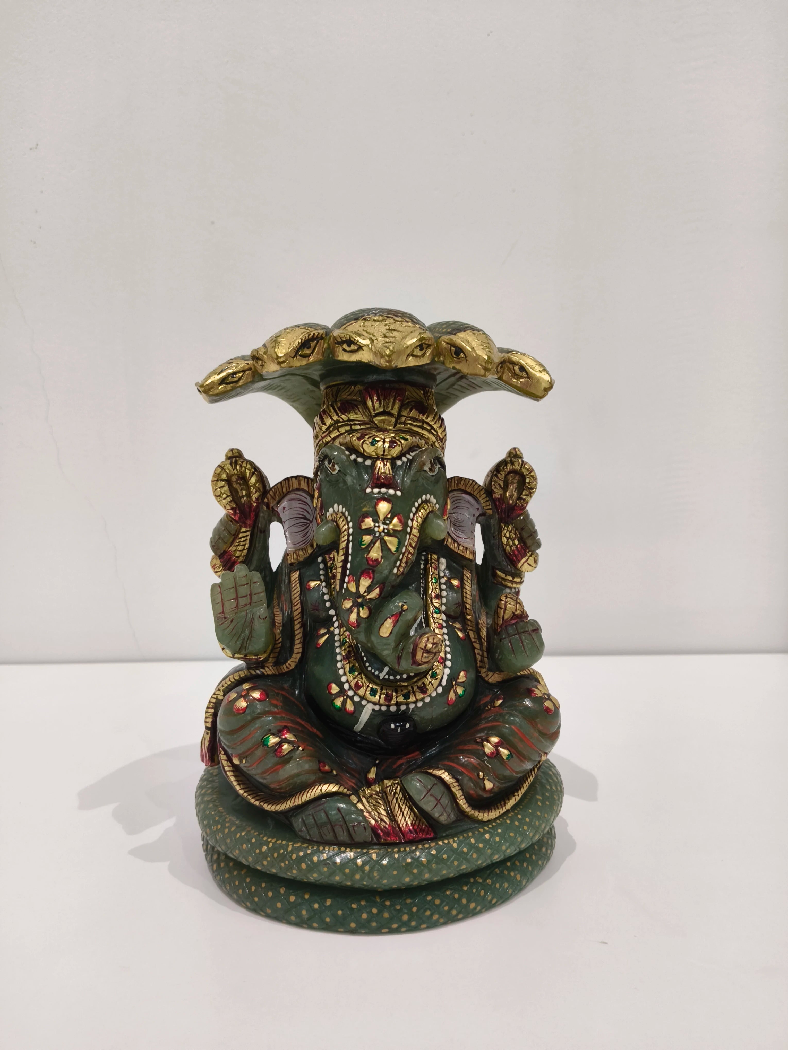 Large jade Ganesh statue with multi-painted details seated under a hood of snakes