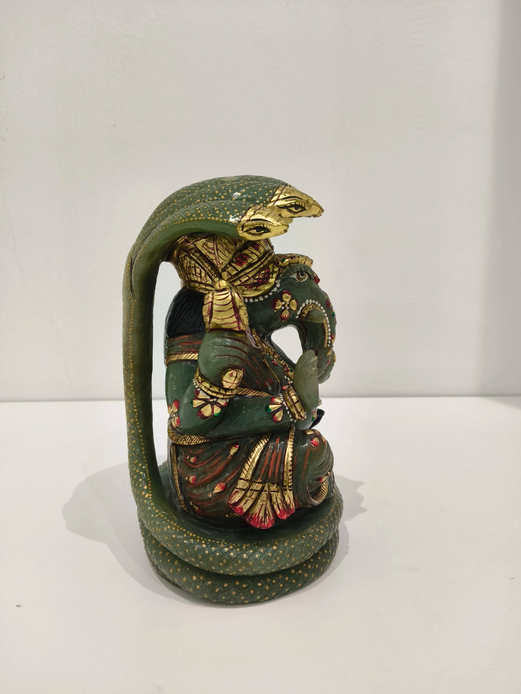 Side view of large jade Ganesh statue with multi-colored paint details