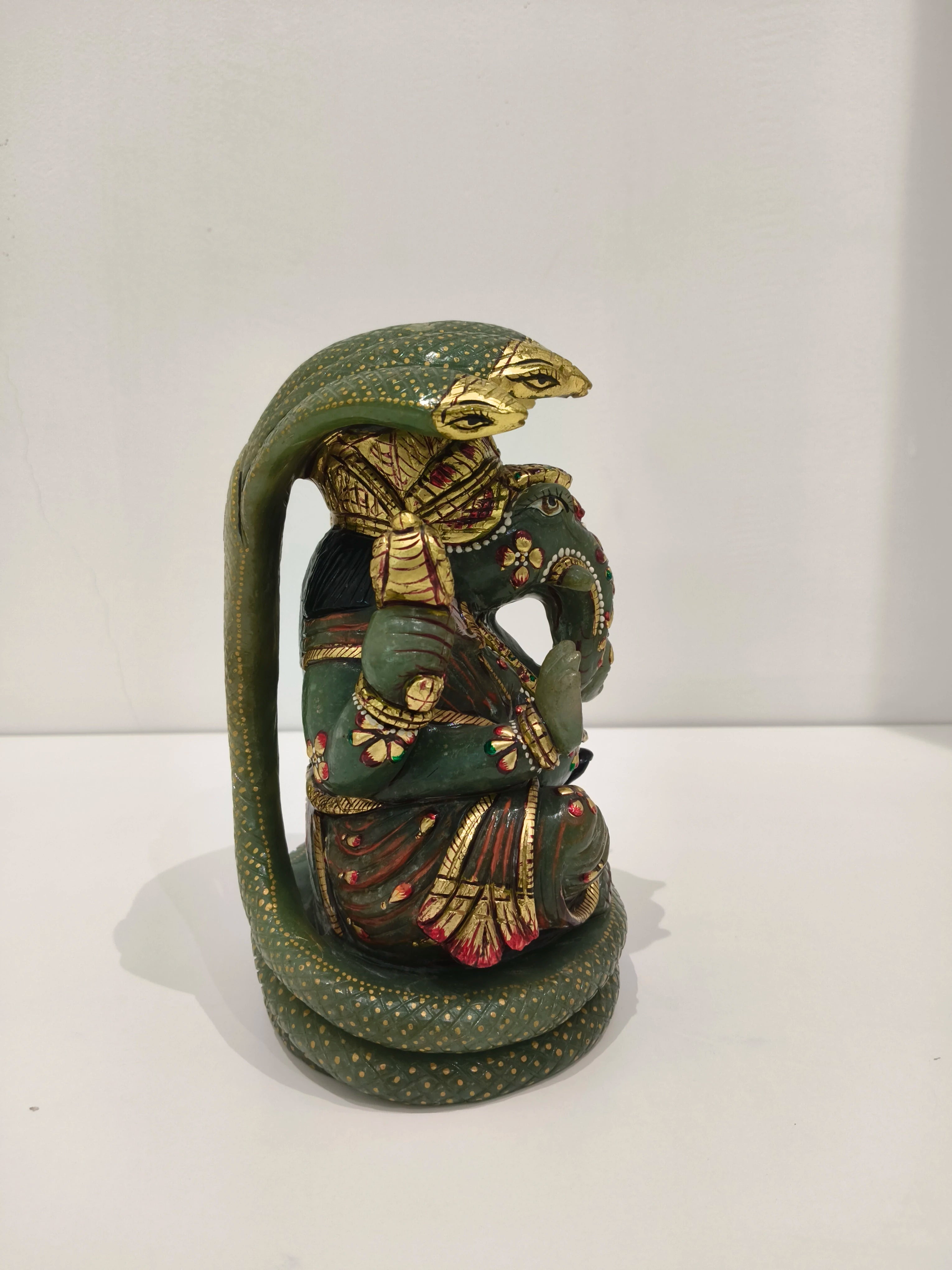 Side view of large jade Ganesh statue with multi-colored paint details