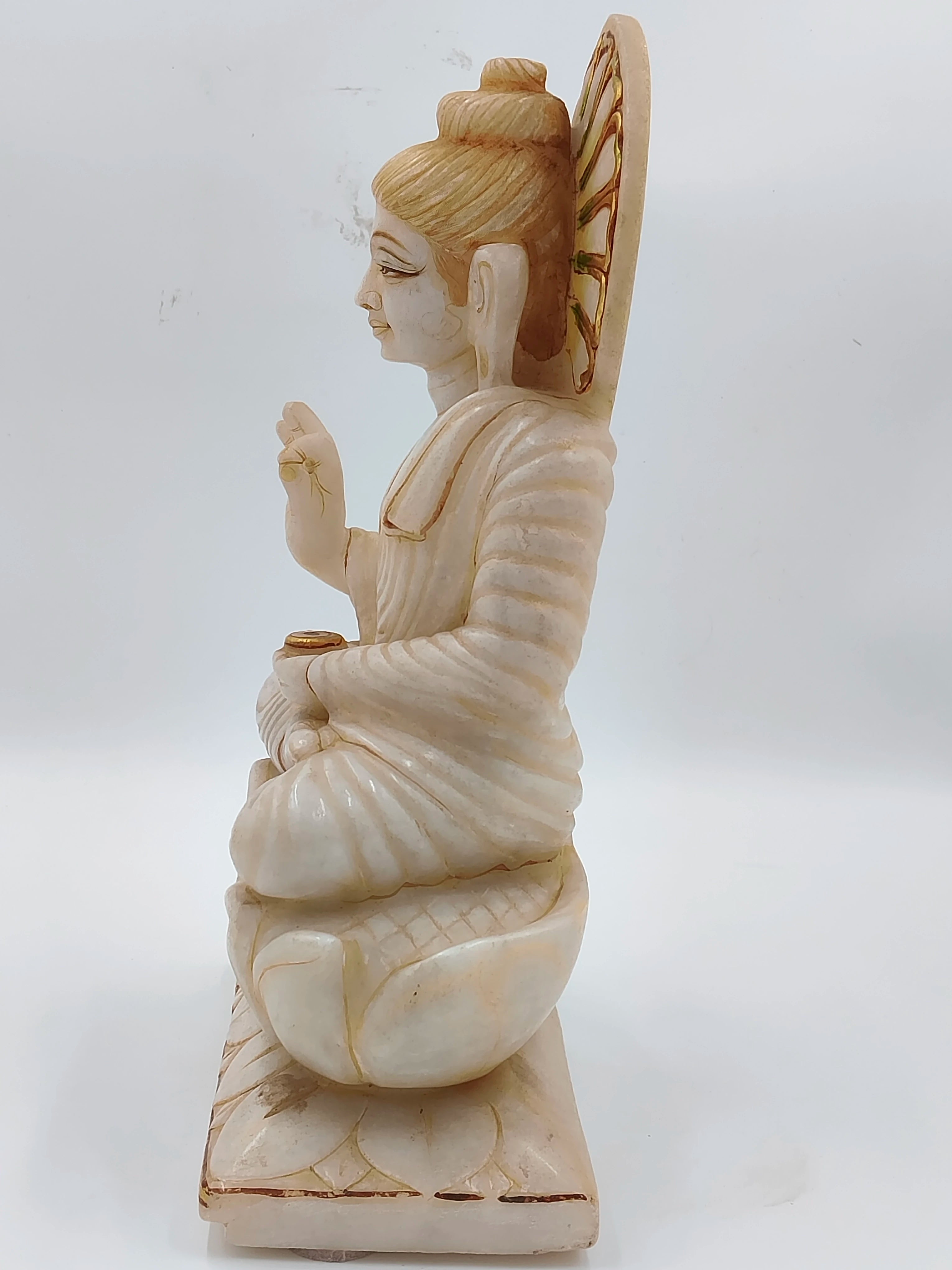 Side view of white marble Buddha statue sitting on lotus base