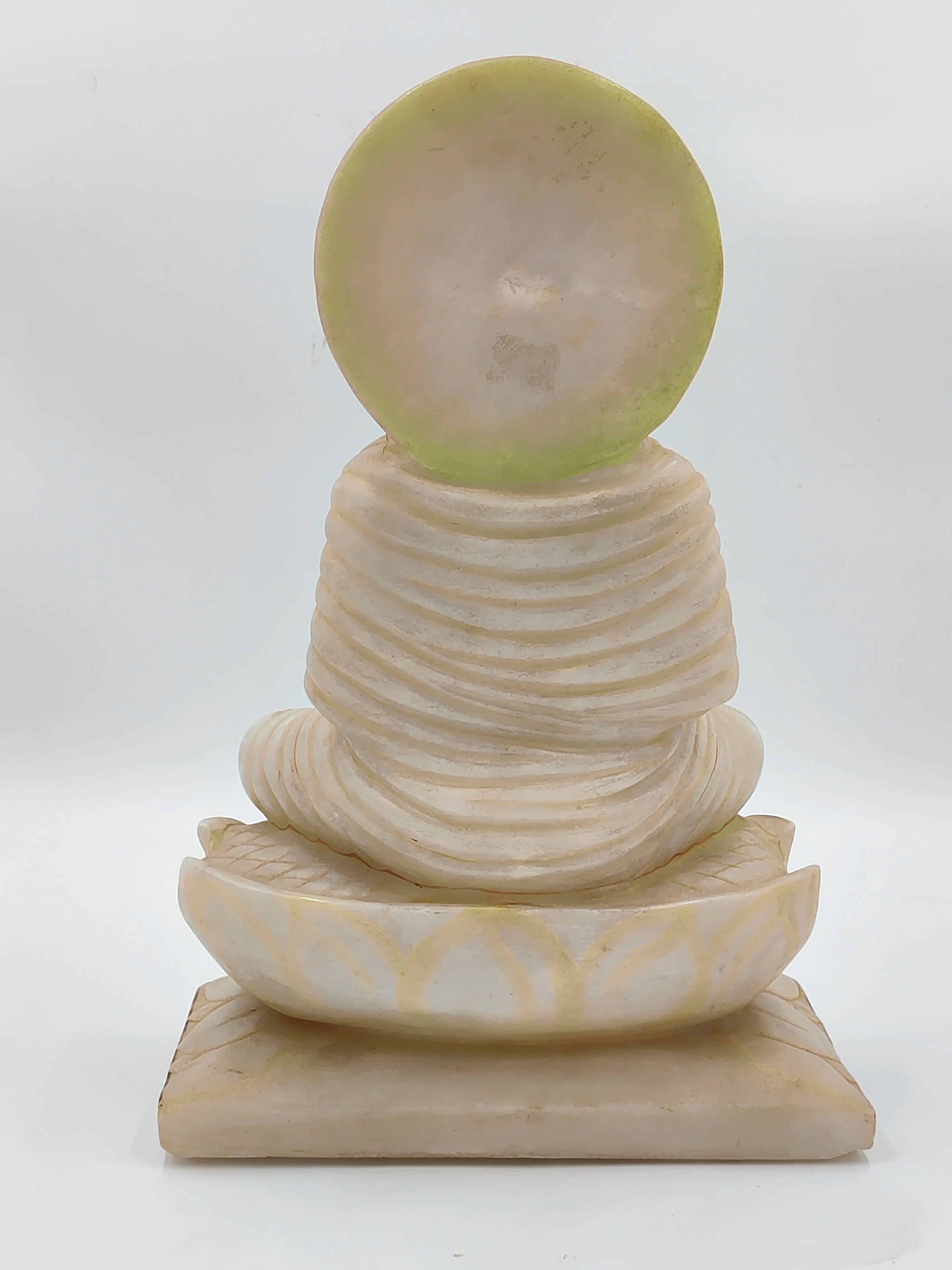Back view of white marble Buddha sculpture seated on lotus base