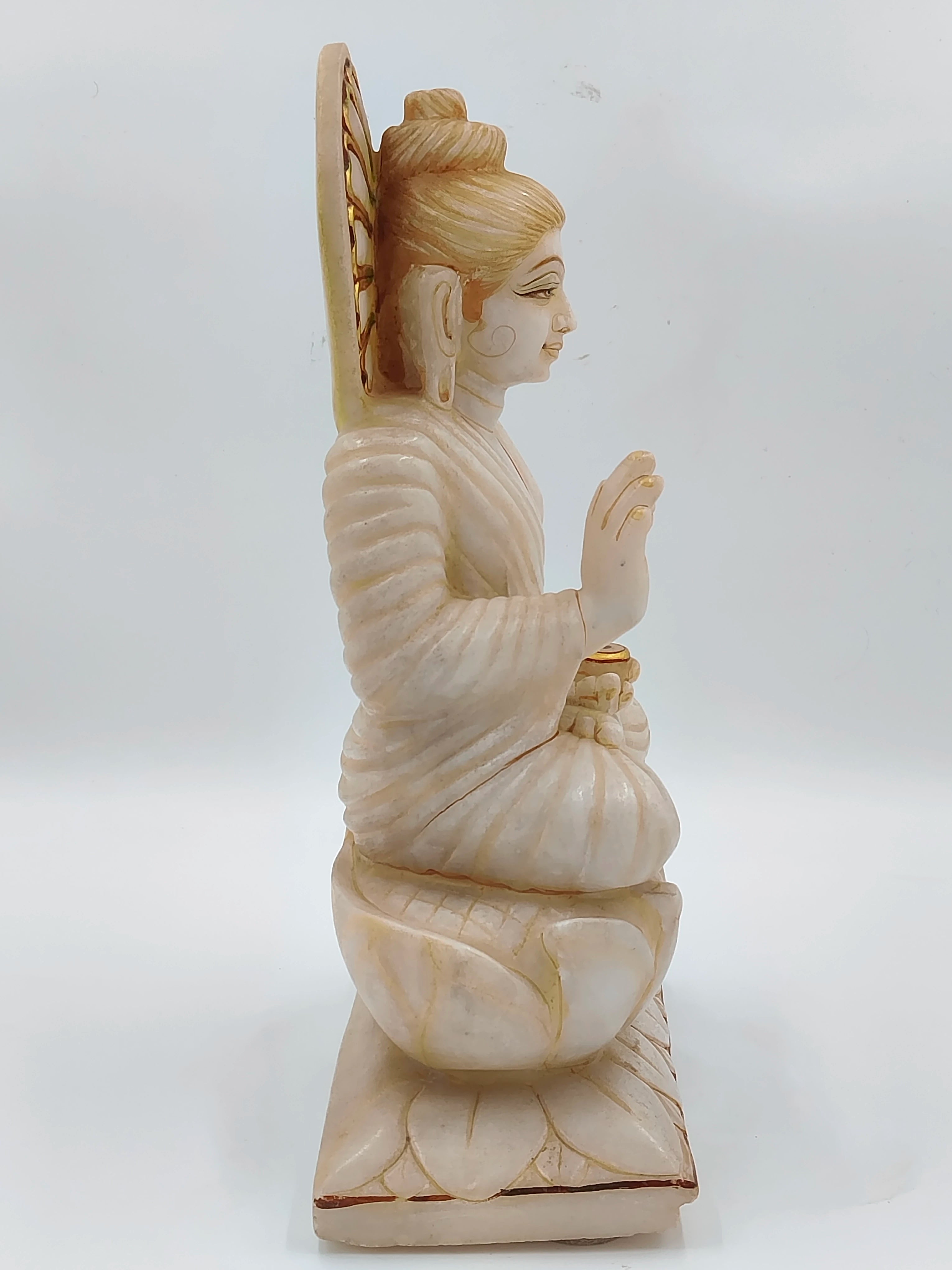 Side view of white marble Buddha statue sitting on lotus pedestal
