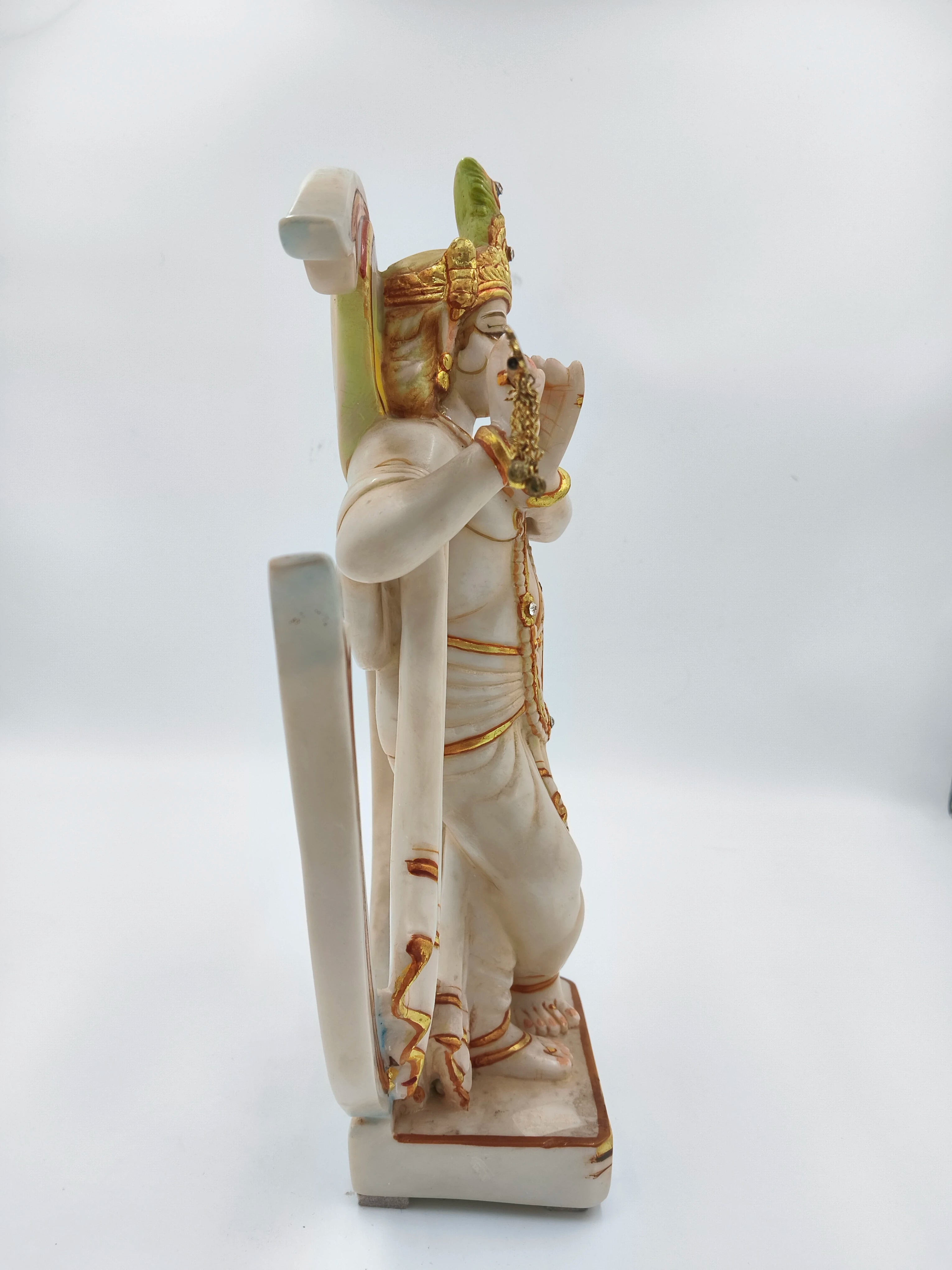 Side view of large marble dust Krishna statue playing flute with Aum symbol backdrop