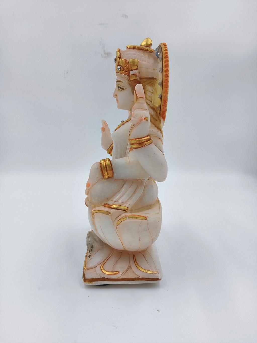 Side view of white marble Lakshmi statue with gold accents sitting on lotus