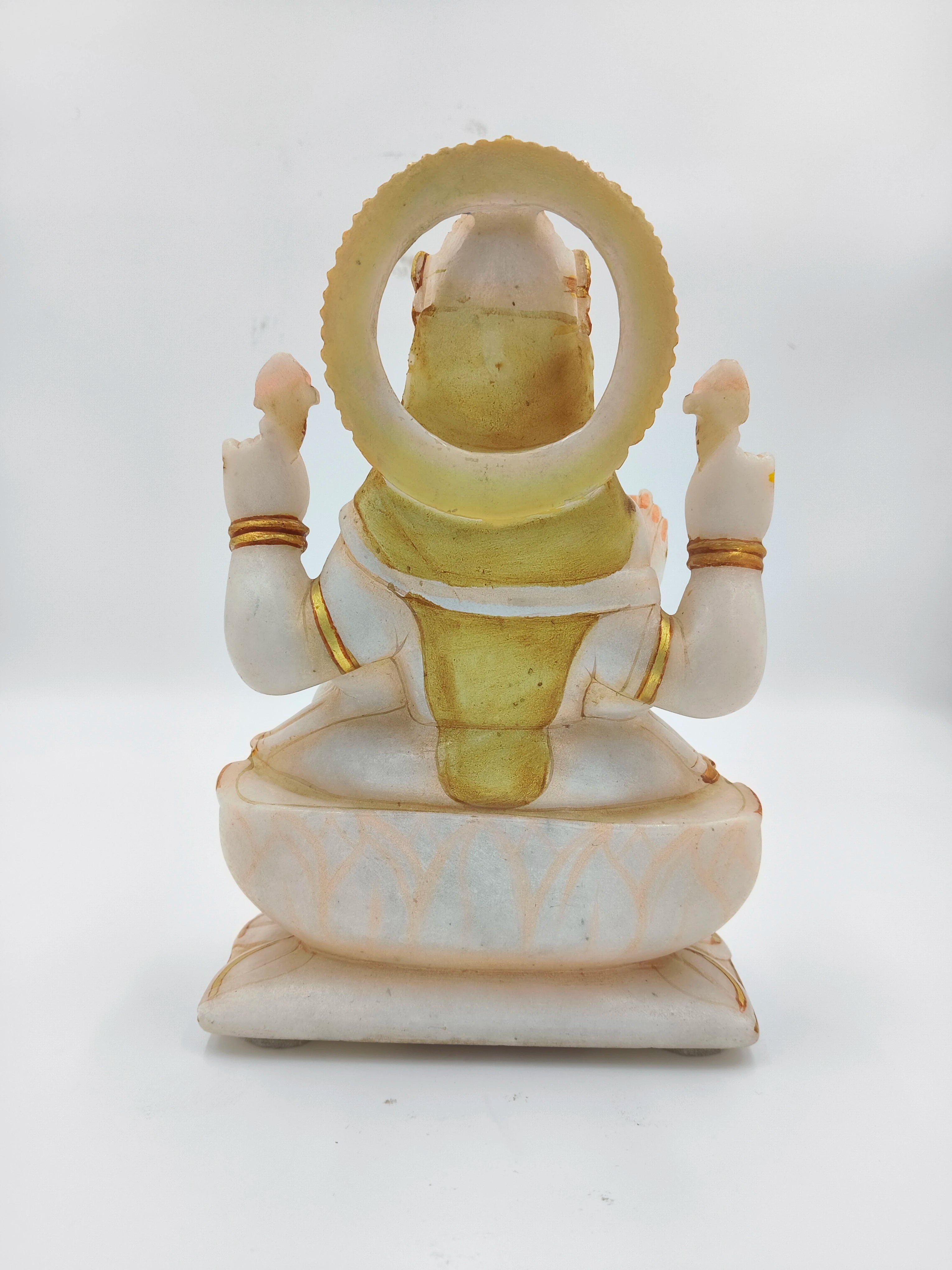 Back view of white marble Lakshmi statue with gold accents sitting on lotus pedestal