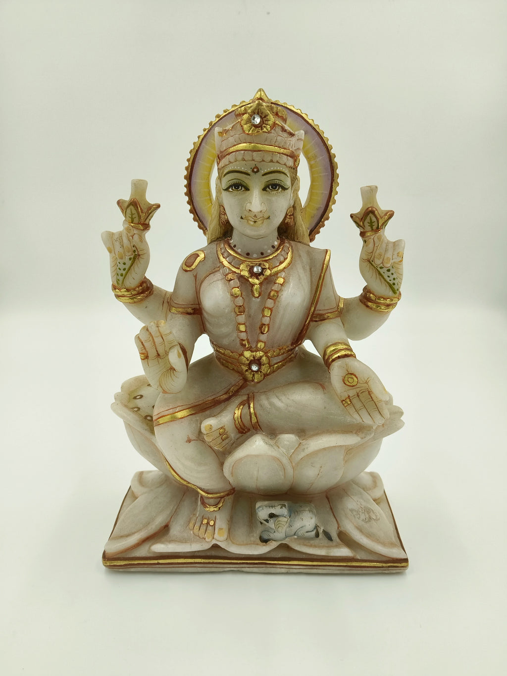 Front view of marble Lakshmi statue with gold and jewel accents seated on lotus