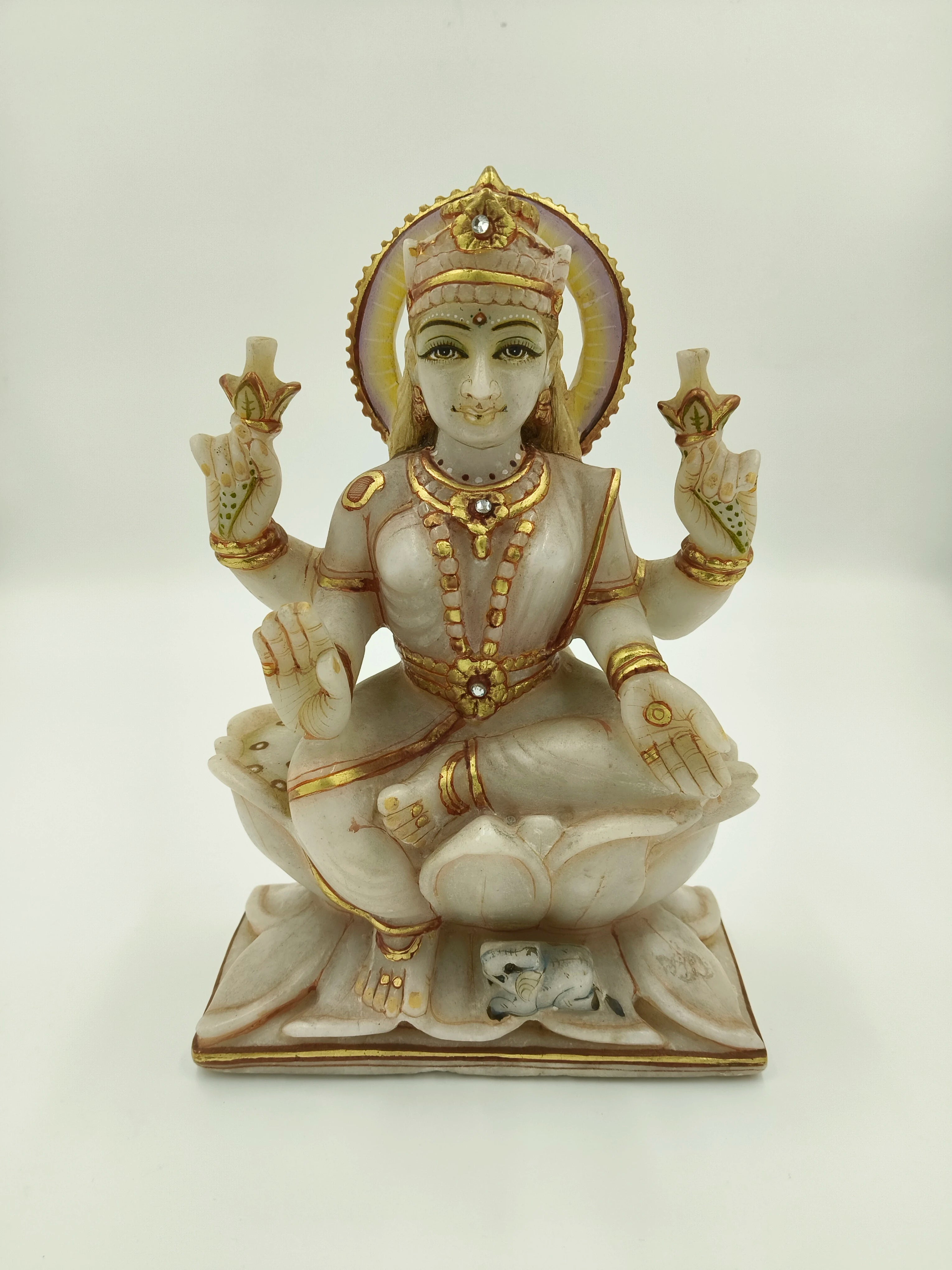 Front view of marble Lakshmi statue with gold and jewel accents seated on lotus