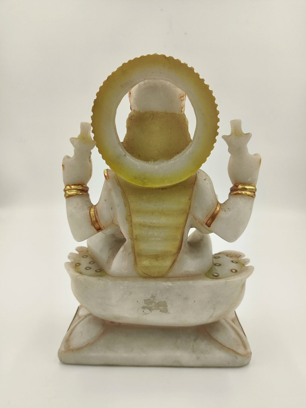 Rear view of marble Lakshmi statue with gold accents and seated posture