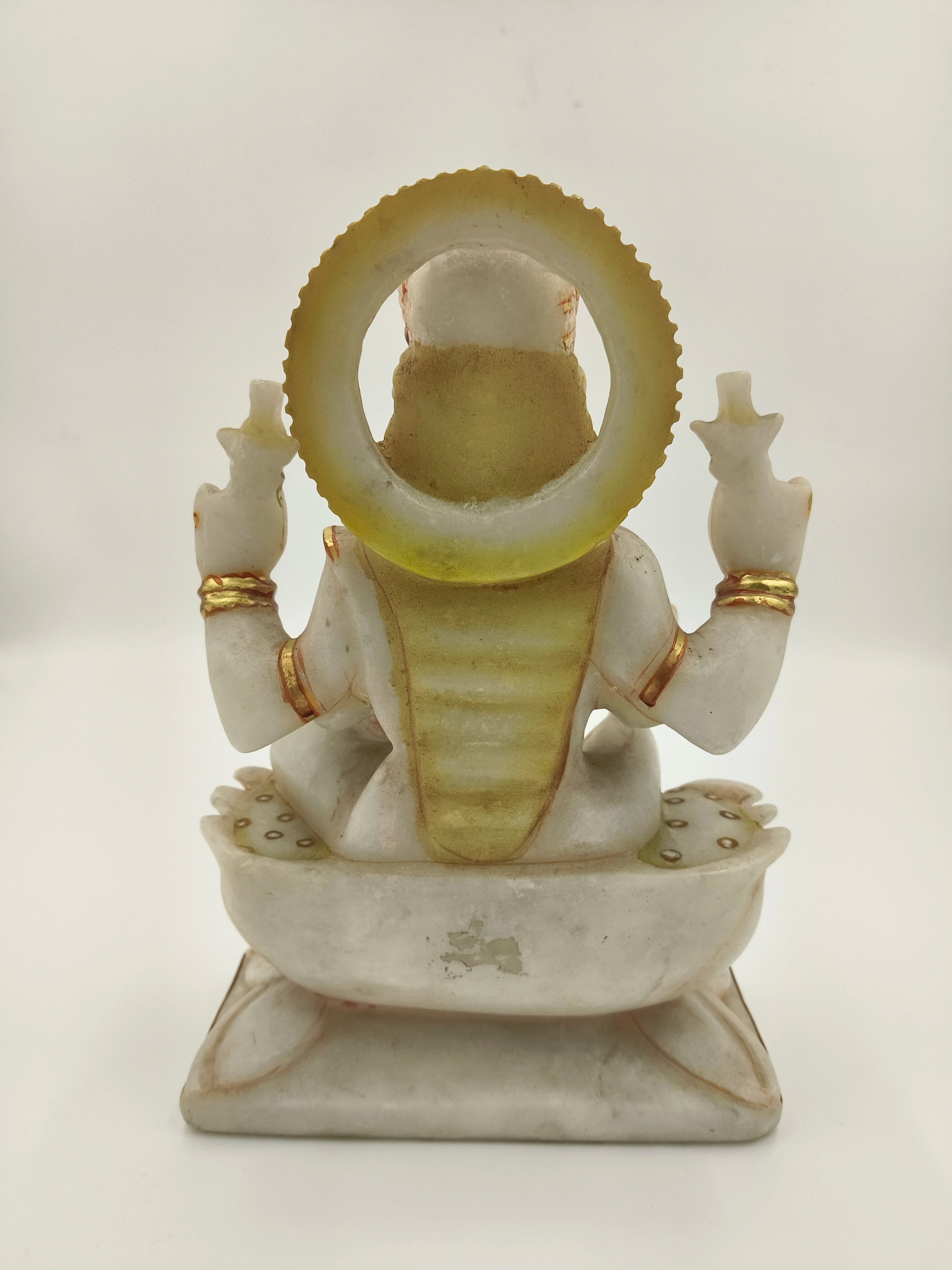 Rear view of marble Lakshmi statue with gold accents and seated posture