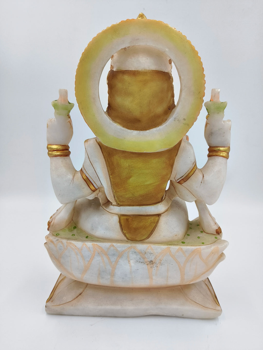 Back view of a large white and gold marble Lakshmi statue seated on a lotus base