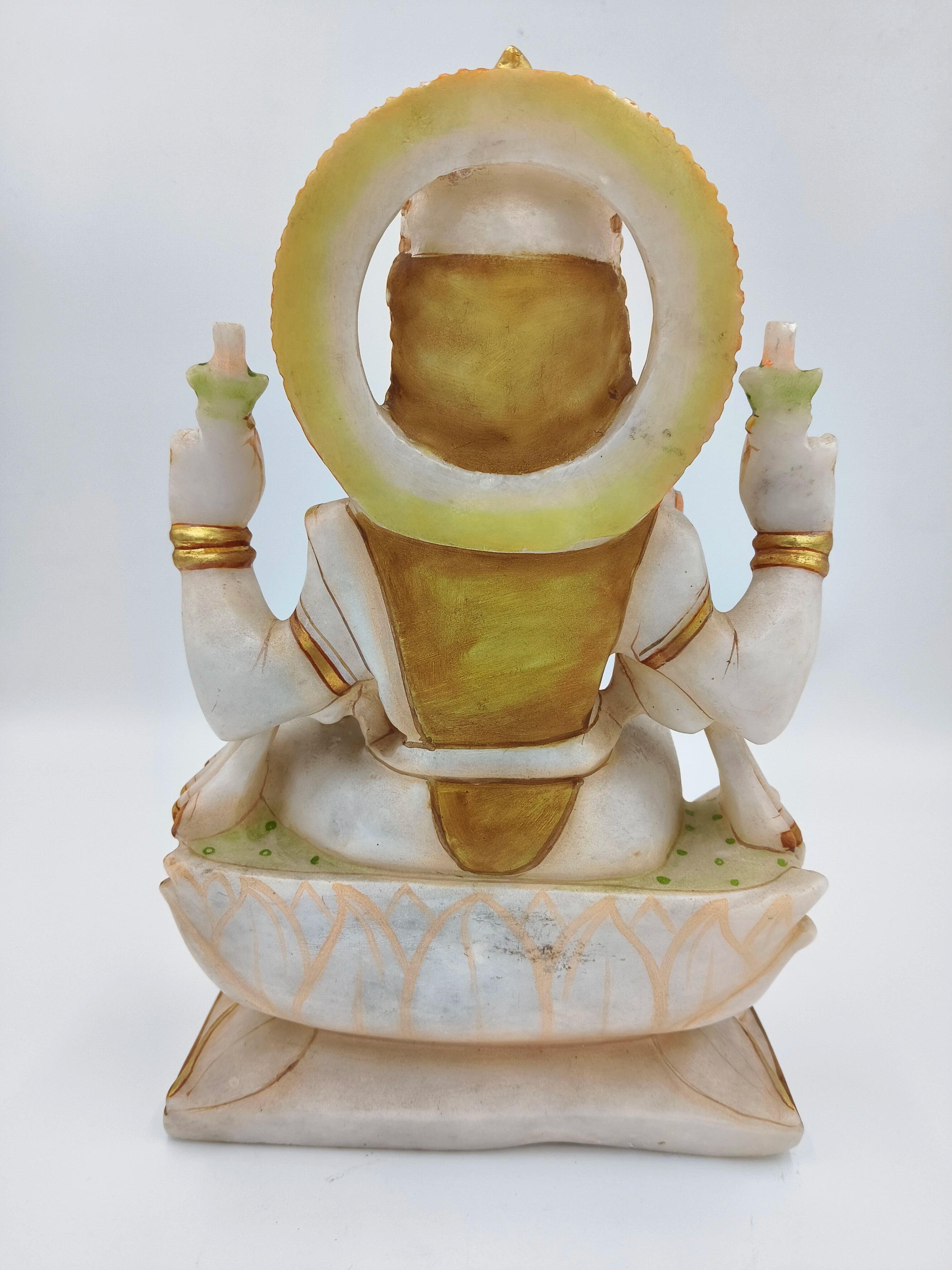 Back view of a large white and gold marble Lakshmi statue seated on a lotus base