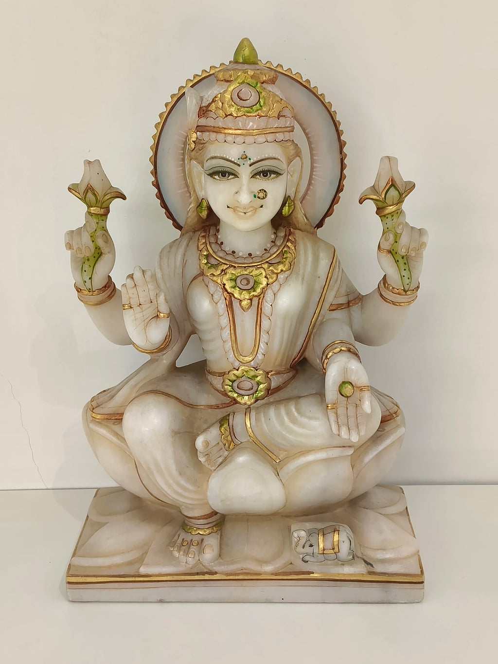 Large marble statue of Lakshmi goddess seated on lotus with gold accents