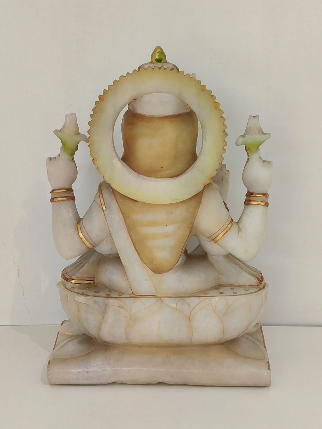 Back view of large marble statue of goddess Lakshmi seated on lotus