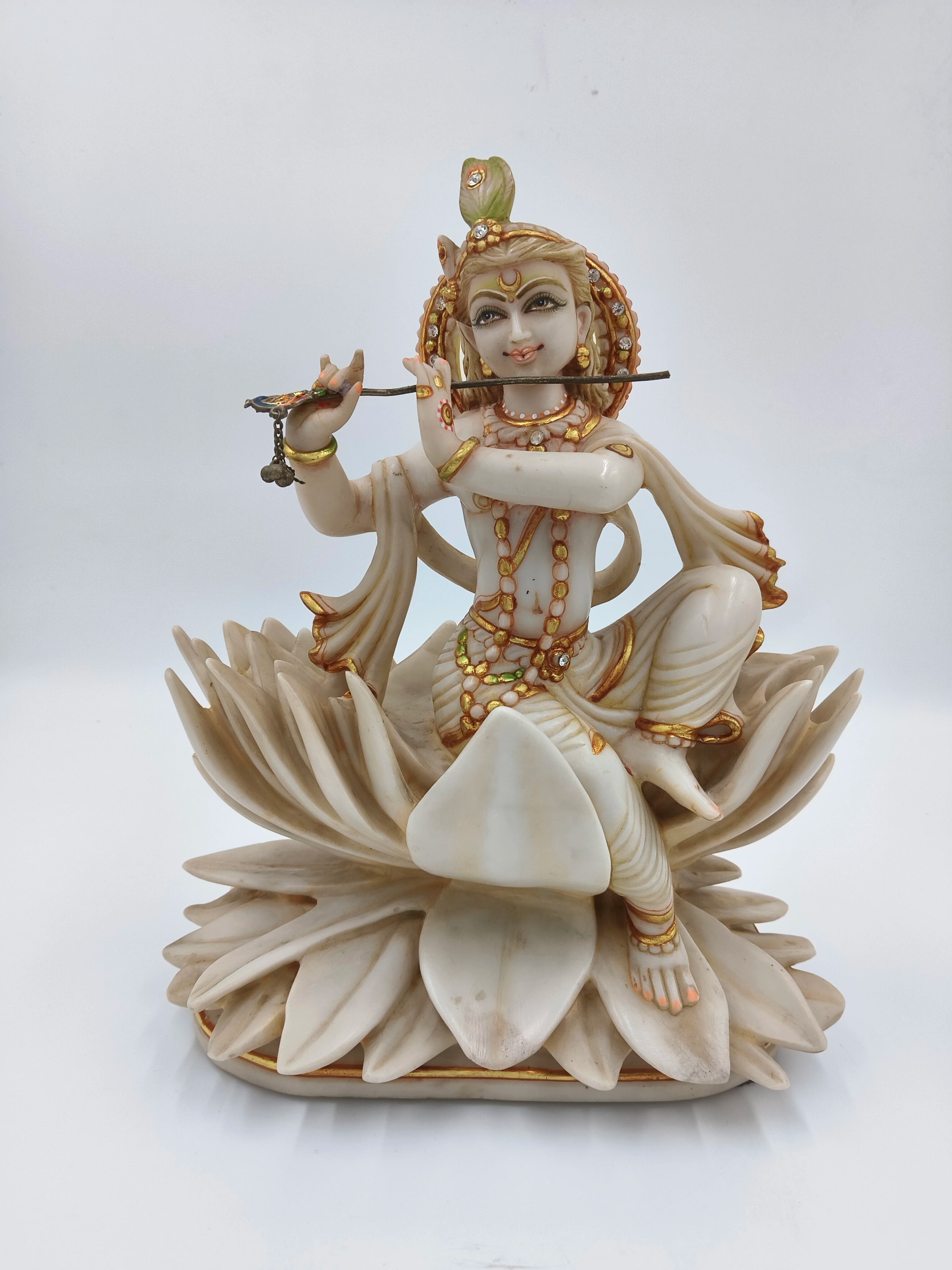 Marble dust statue of Krishna sitting on a lotus, playing flute