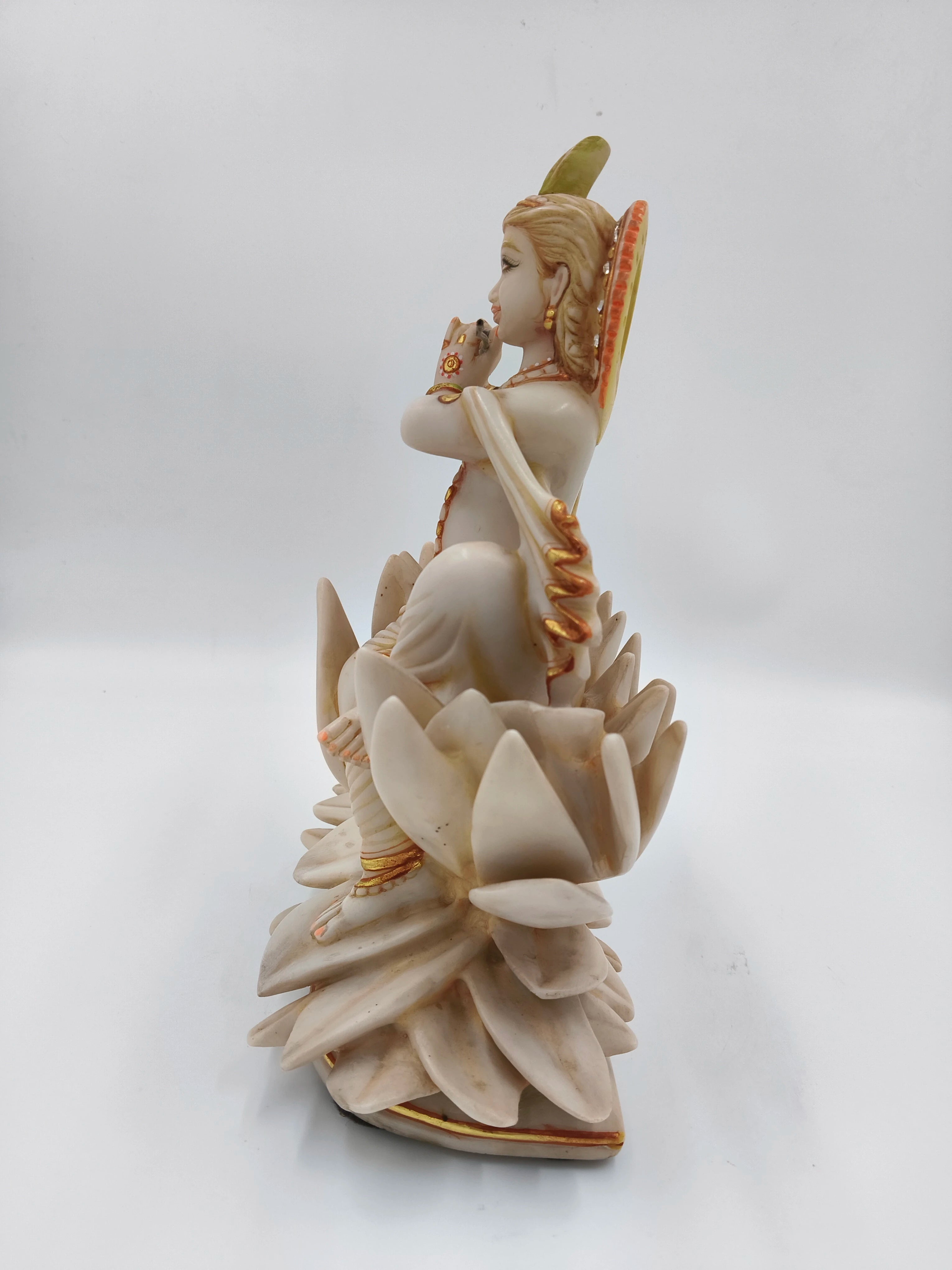 Side view of marble dust Krishna sculpture sitting on lotus with detailed petals