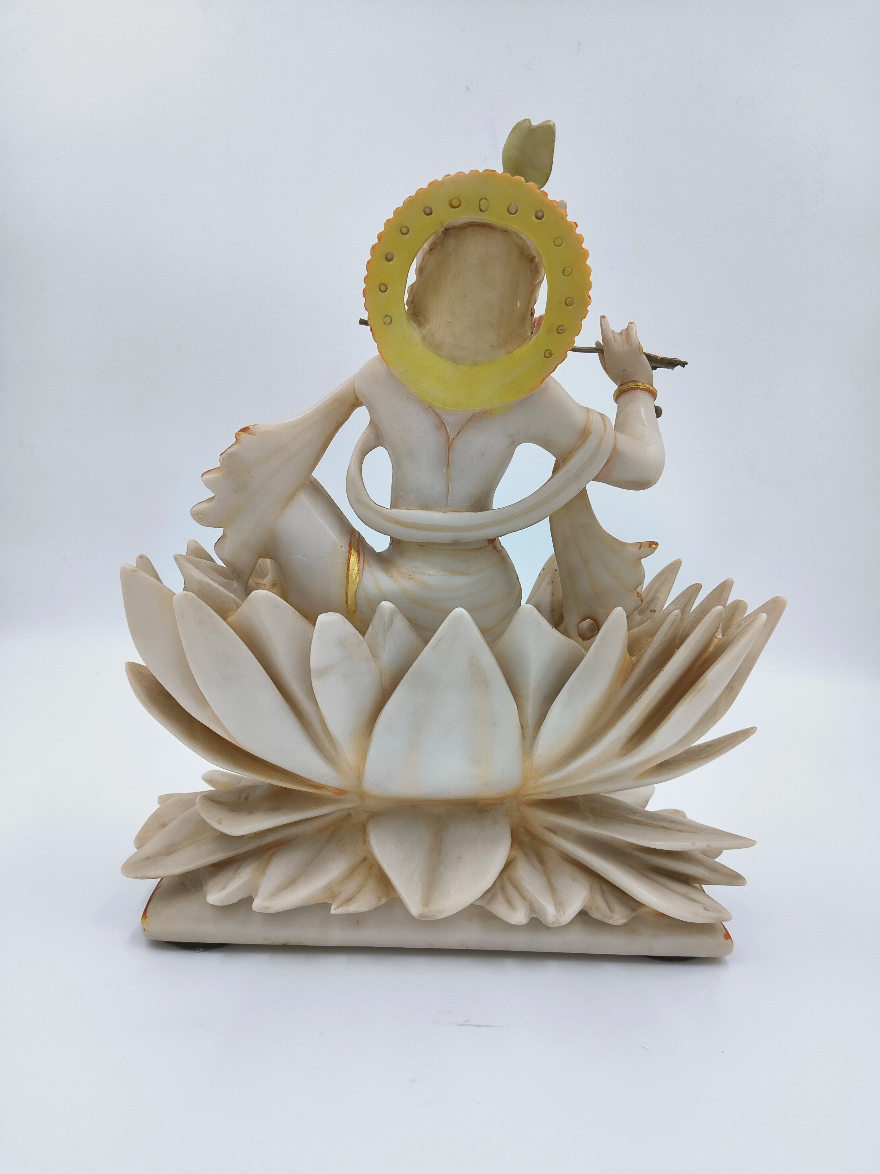 Back view of marble dust Krishna sculpture sitting on a lotus with flute