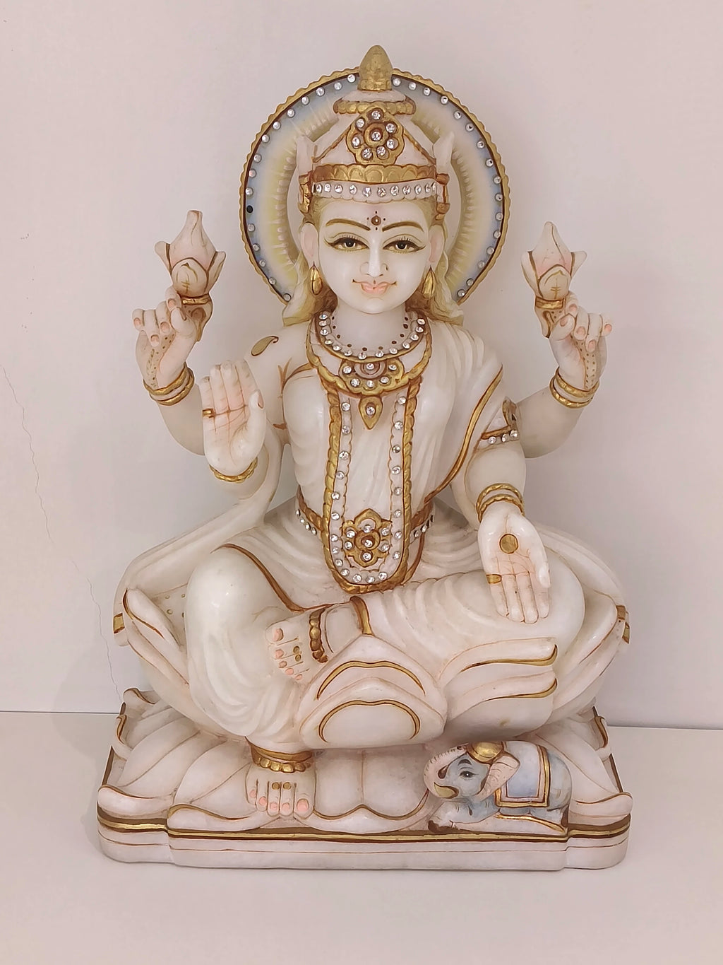 Marble statue of Goddess Lakshmi seated with four arms holding lotus flowers