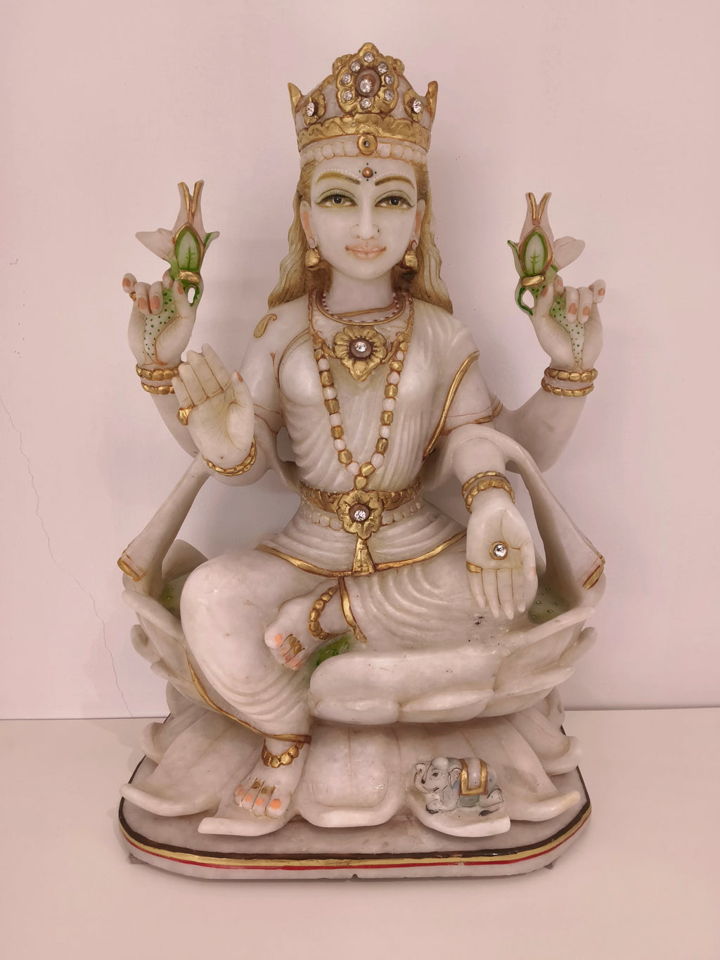 White marble statue of goddess Lakshmi seated on a lotus with gold accents