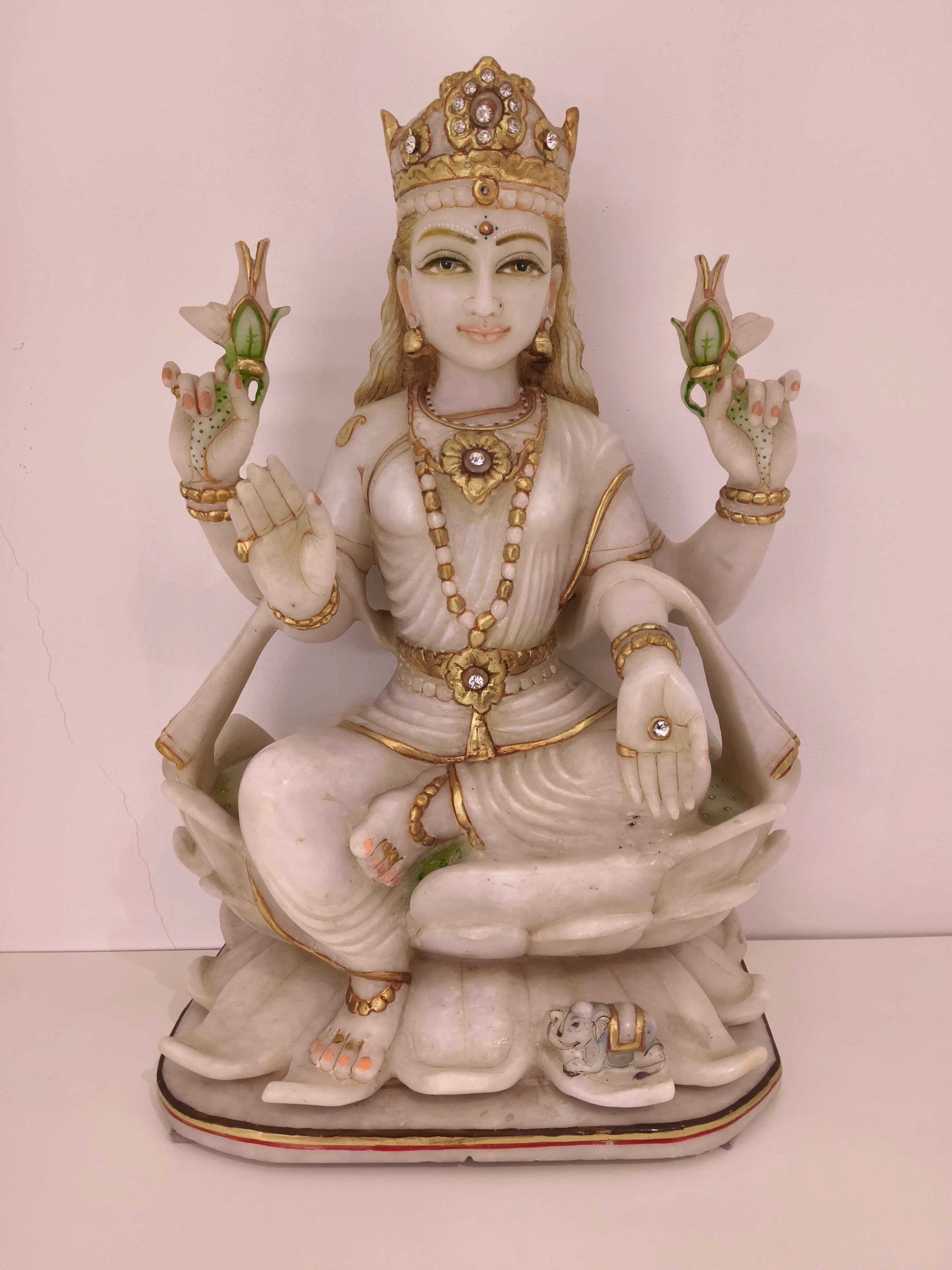 White marble statue of goddess Lakshmi seated on a lotus with gold accents