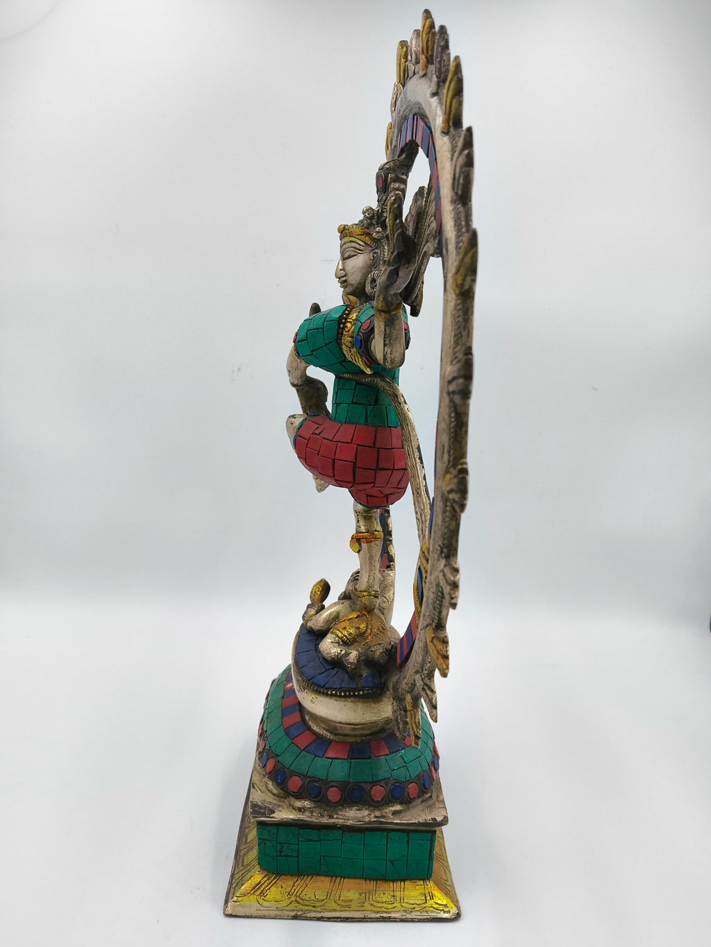Side view of large brass Nataraja statue with colorful inlays and decorative base