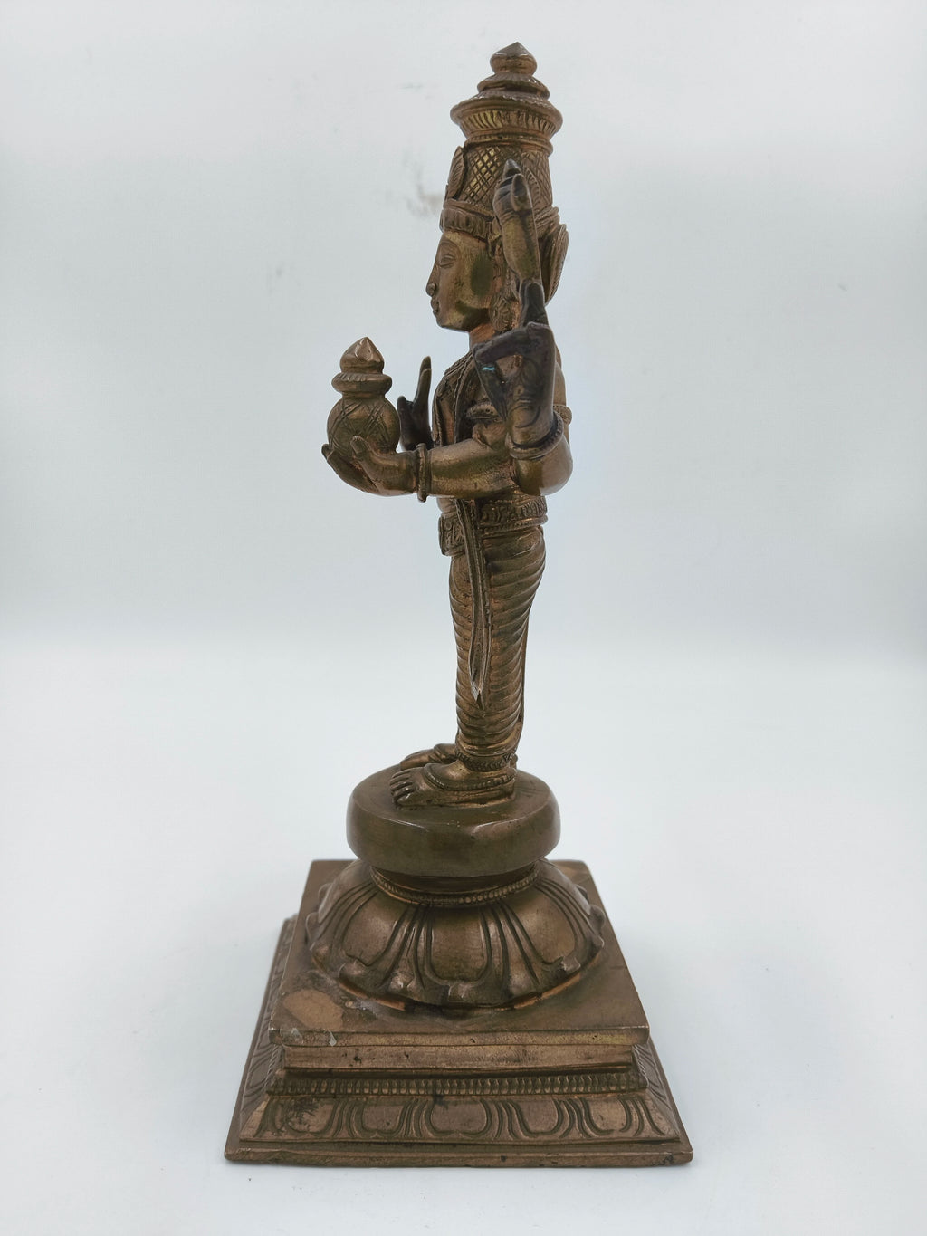 Side view of bronze Vishnu statue standing on ornate base