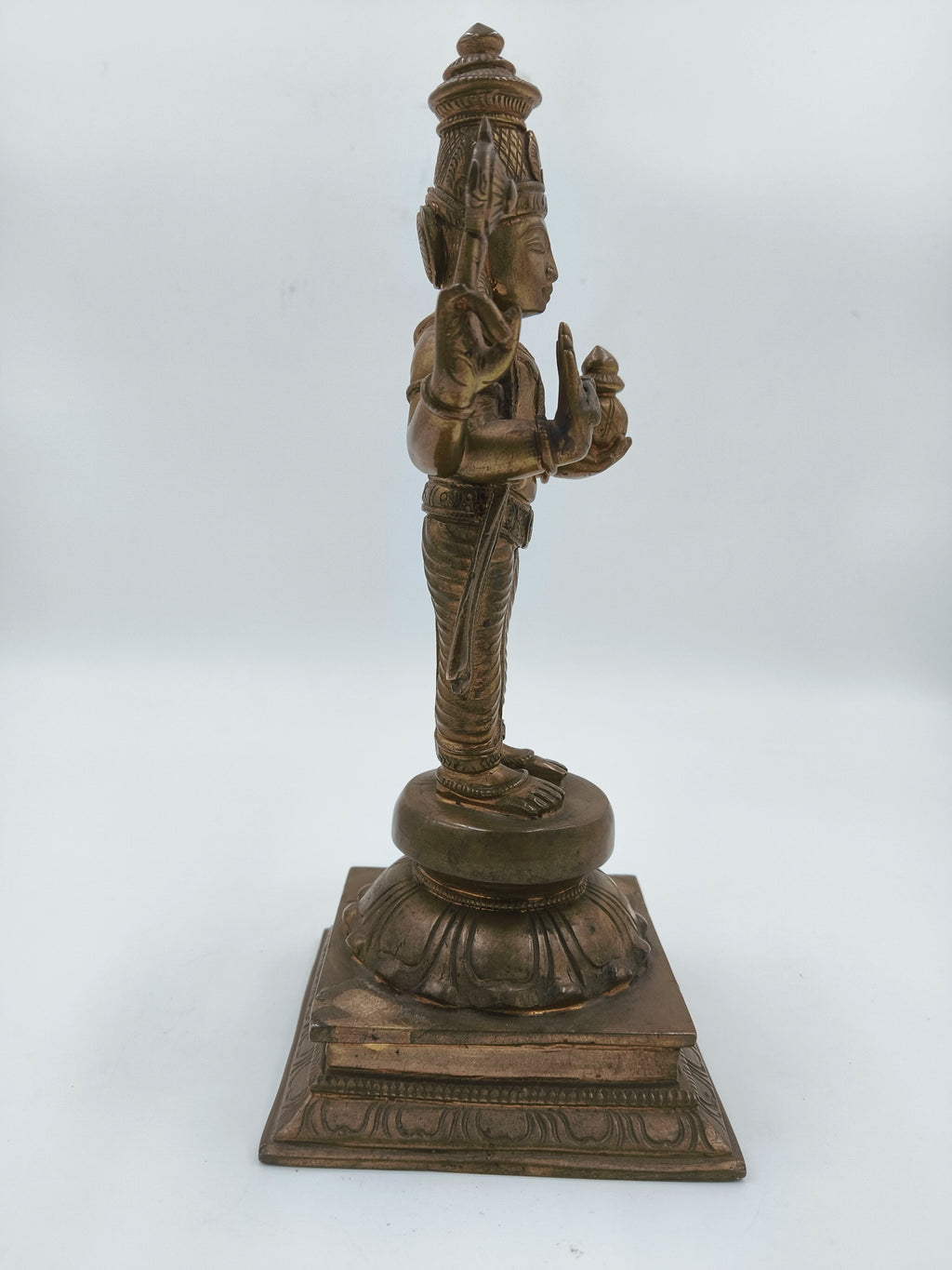 Side view of bronze Vishnu sculpture standing on decorated pedestal