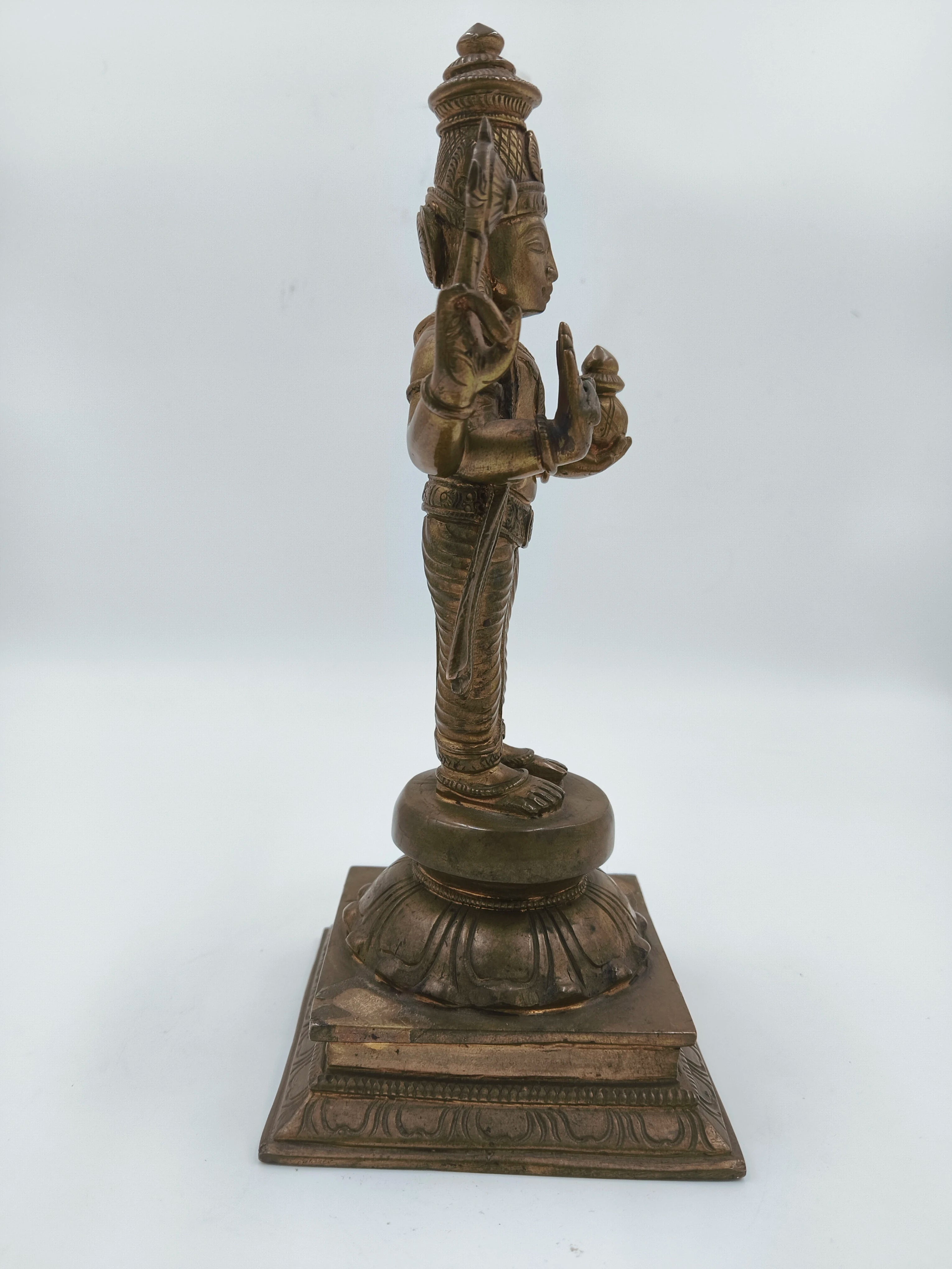 Side view of bronze Vishnu sculpture standing on decorated pedestal
