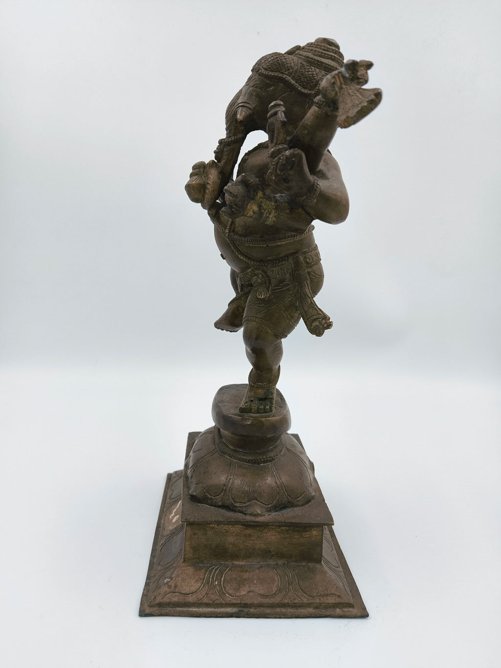 Large brass sculpture of dancing Ganesh standing on ornate square base
