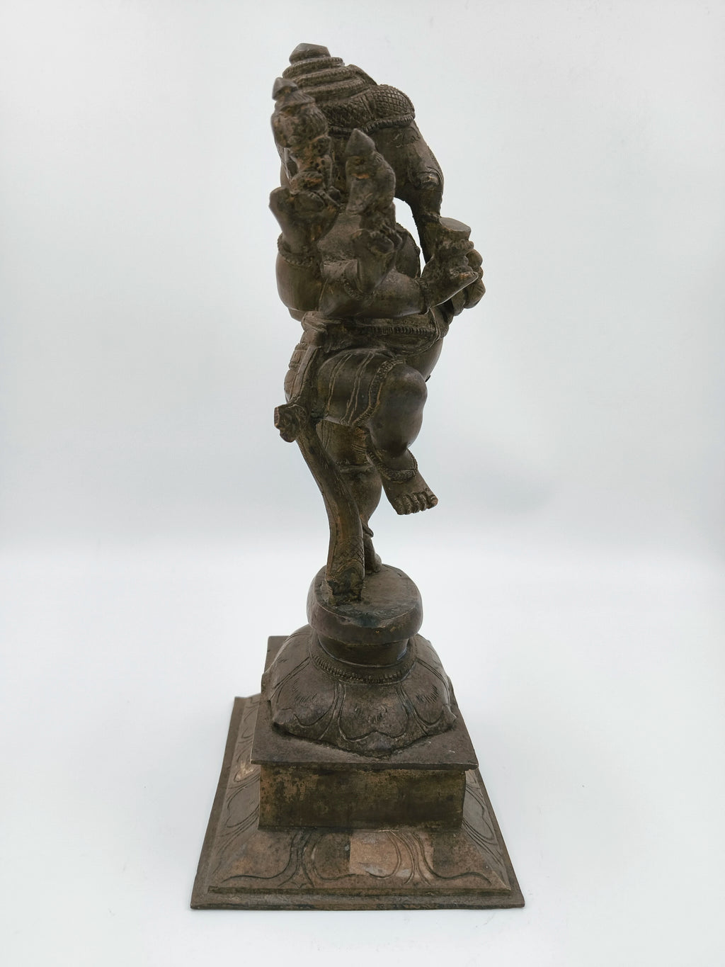 Side view of large brass bronze statue of dancing Ganesh on decorative base