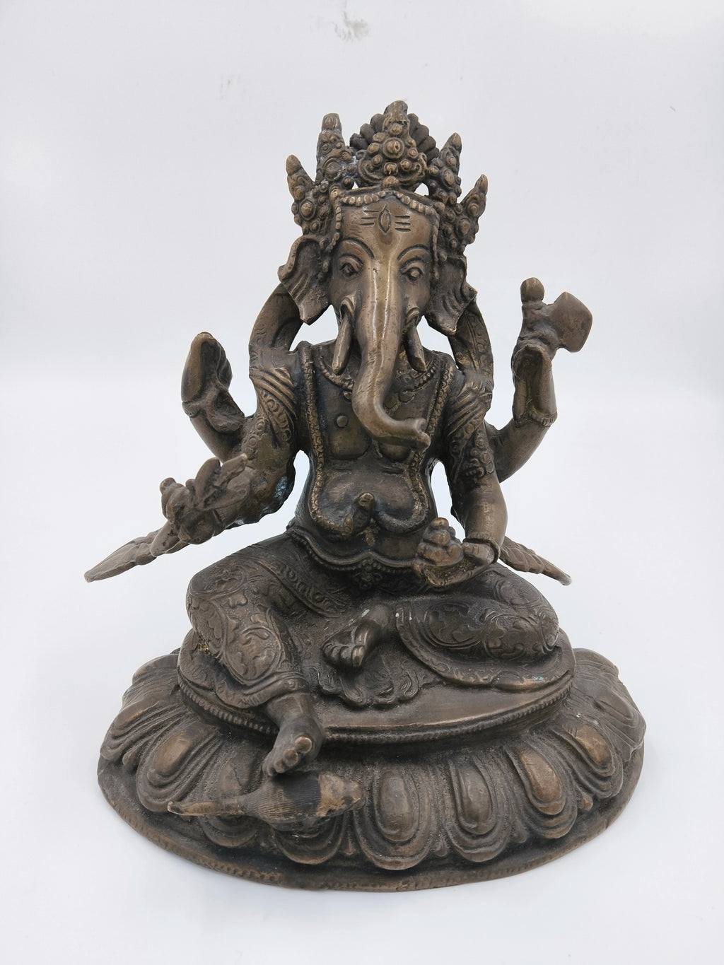 Brass statue of Ganesh seated on ornate base with detailed carvings