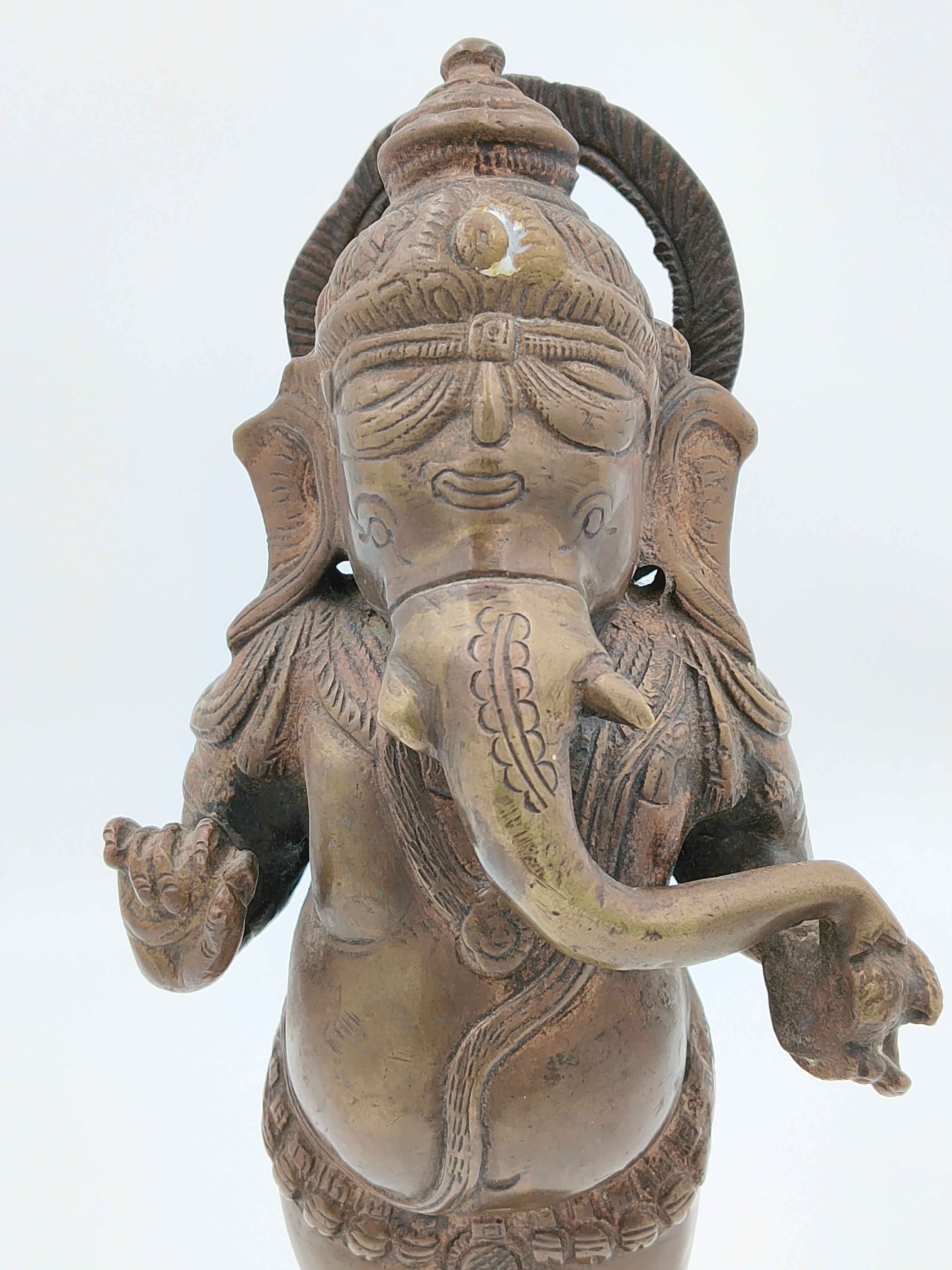 Close-up front view of a brass standing Ganesh statue with detailed engravings