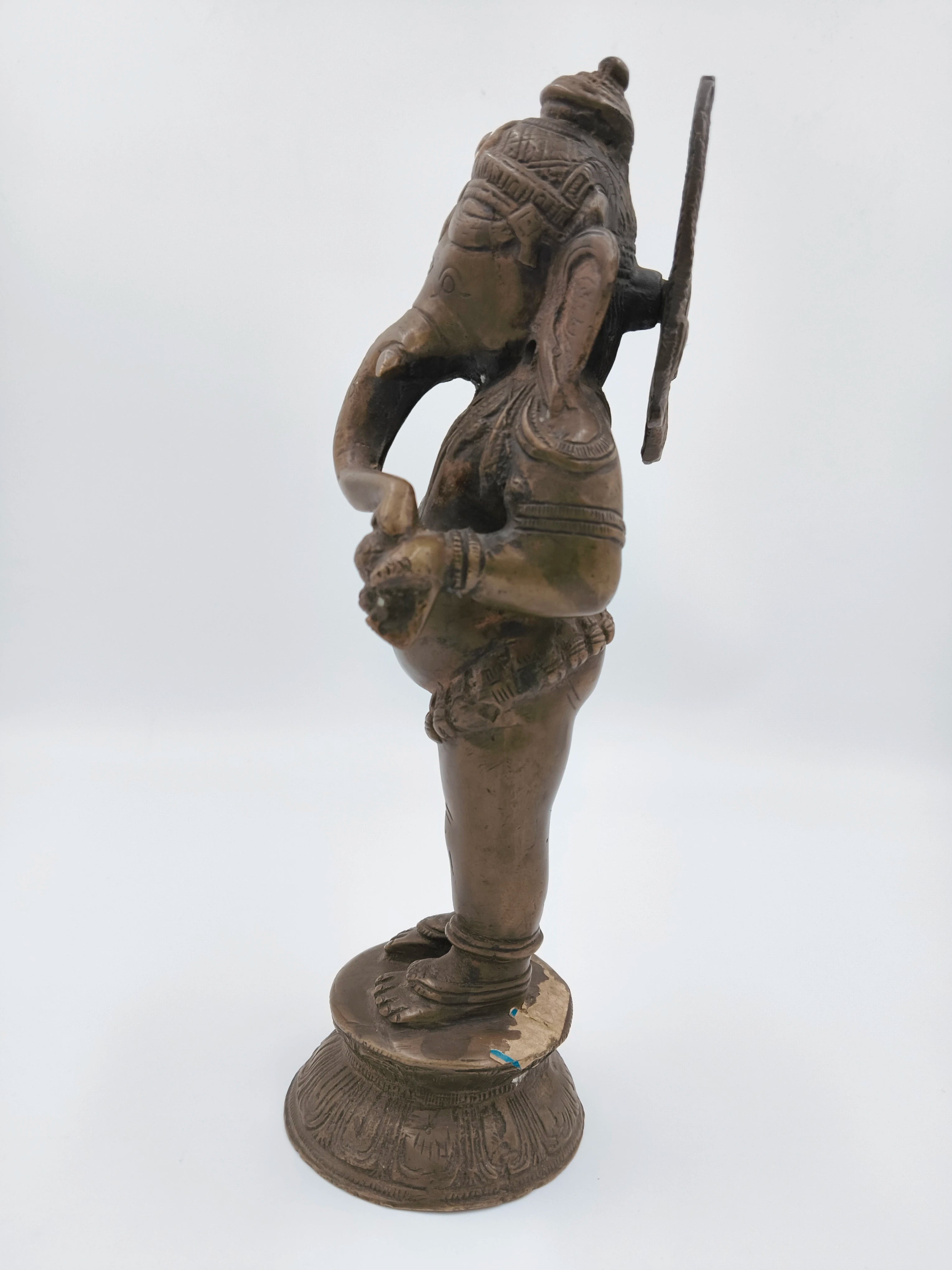 Side view of brass standing Ganesh statue with detailed carvings