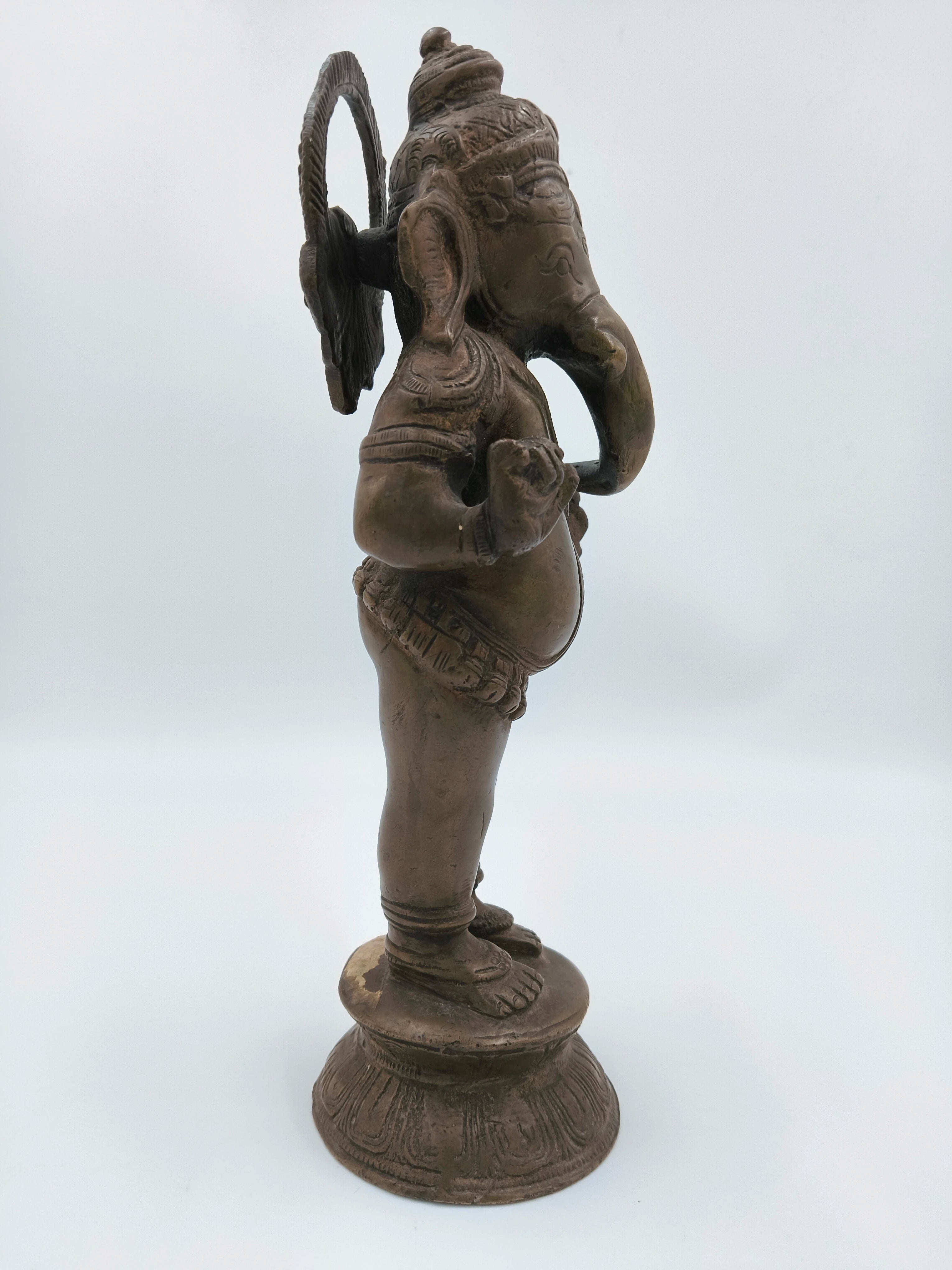 Side view of a large brass standing Ganesh statue on a round base