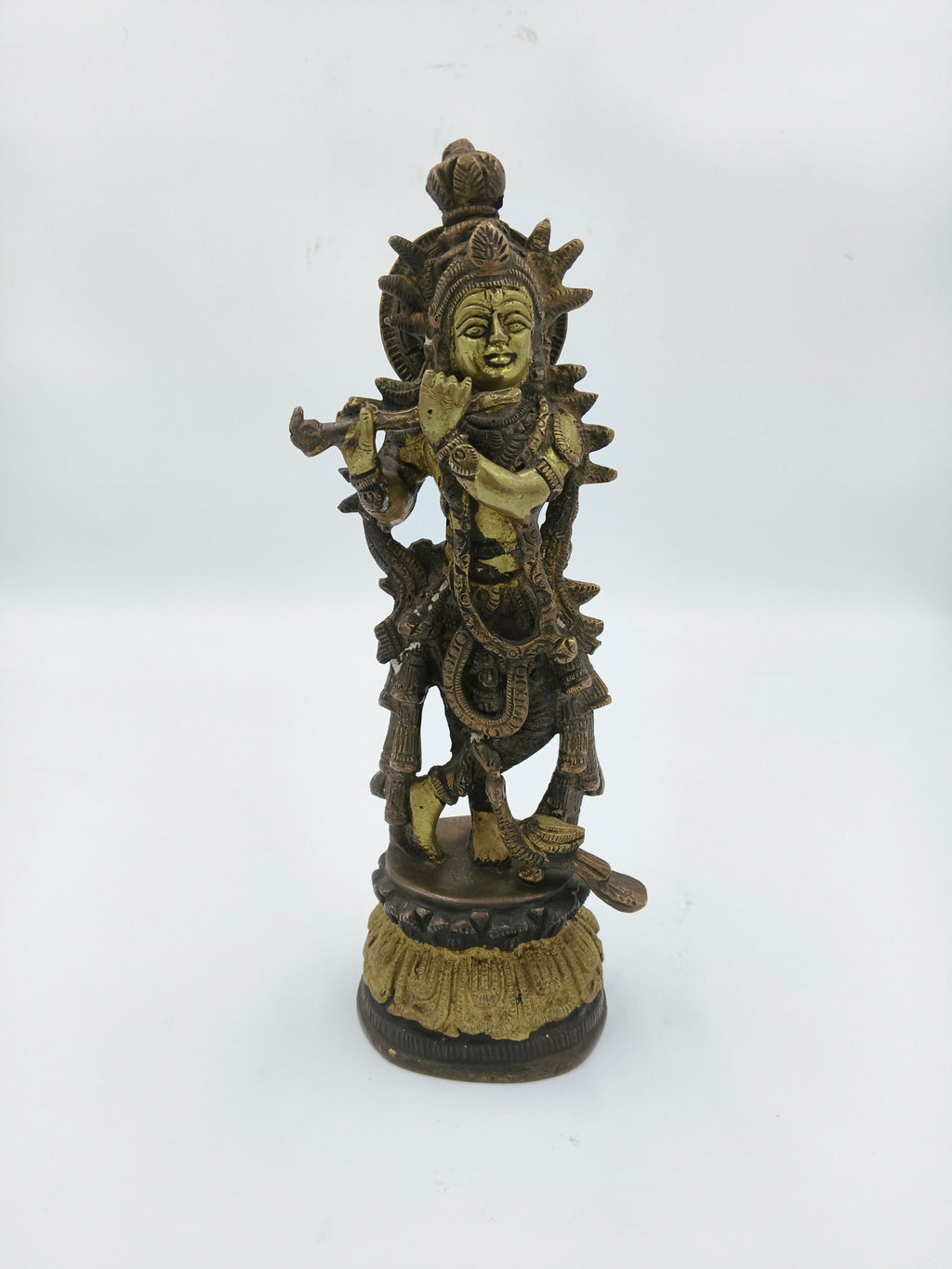 Large brass sculpture of Krishna playing flute with intricate detailing on pedestal