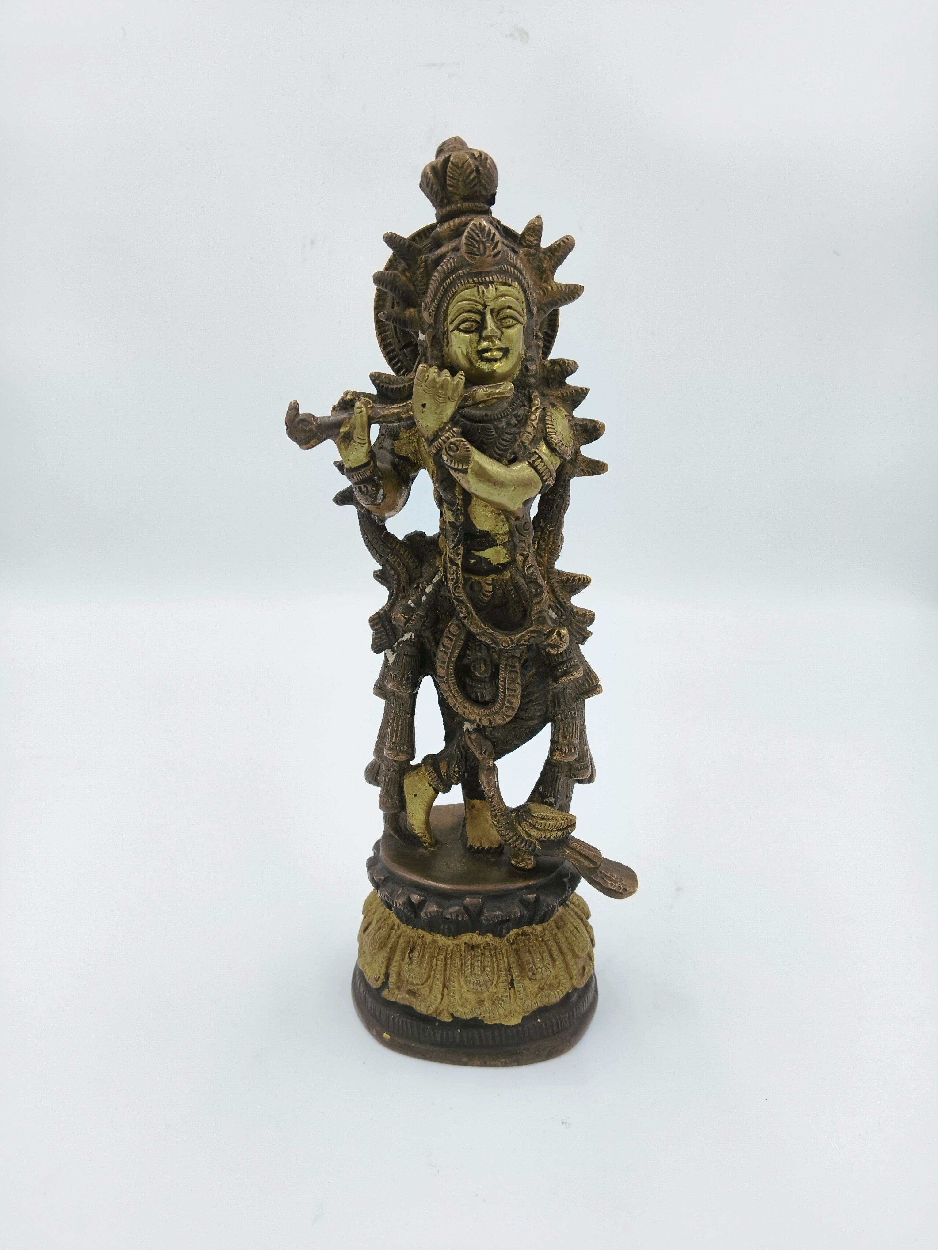 Large brass sculpture of Krishna playing flute with intricate detailing on pedestal